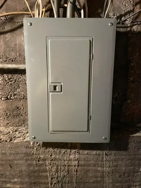 A white electrical box is hanging on a wall.