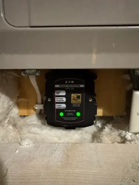 A black device is sitting underneath a washer and dryer.