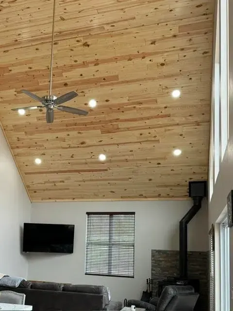 A living room with a wooden ceiling and a ceiling fan.