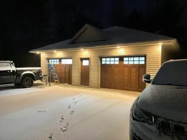 A car is parked in front of a garage at night.