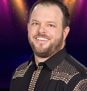 A man with a beard is wearing a black shirt with gold studs