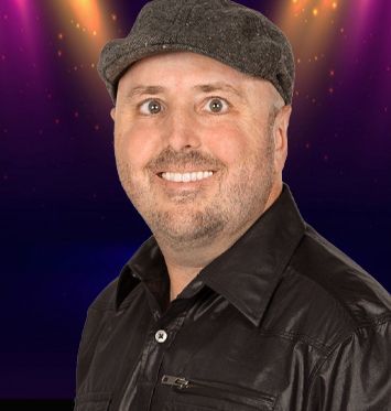 A man wearing a hat and a black shirt is smiling.