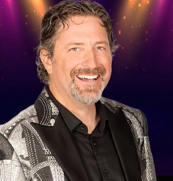 A man with a beard is wearing a tuxedo and smiling.