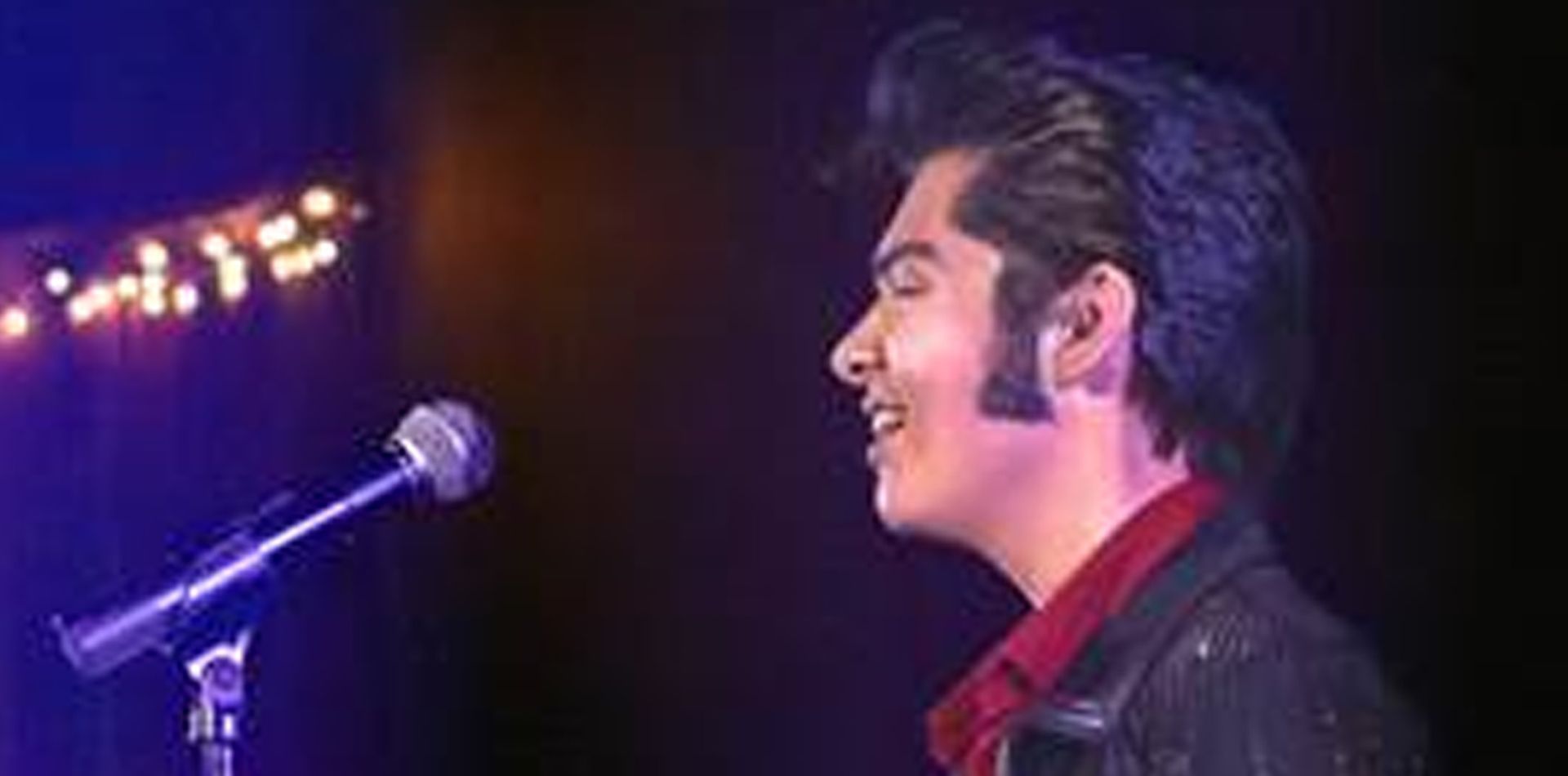 A man is singing into a microphone on a stage.