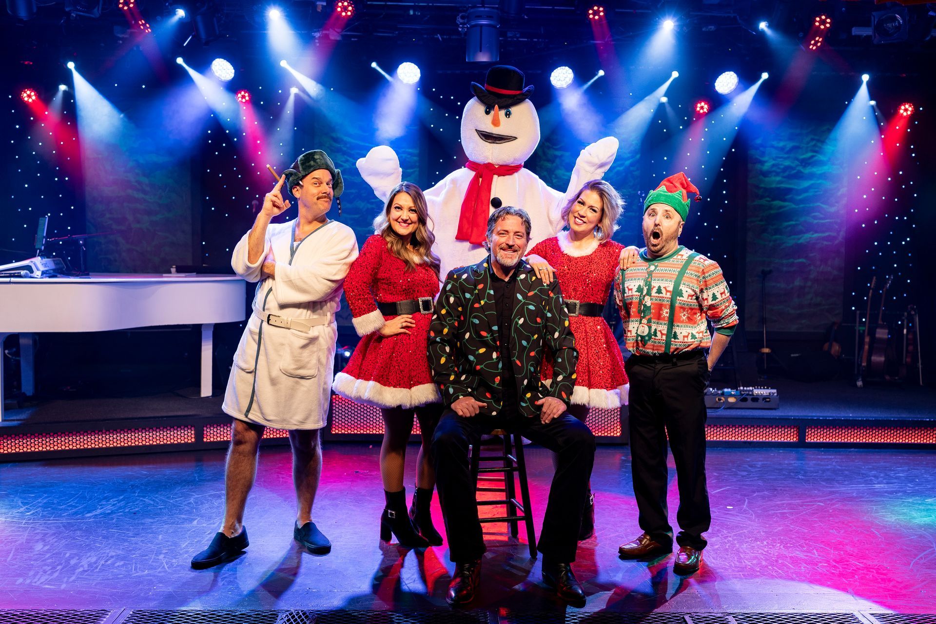 A group of people are standing on a stage in front of a snowman.