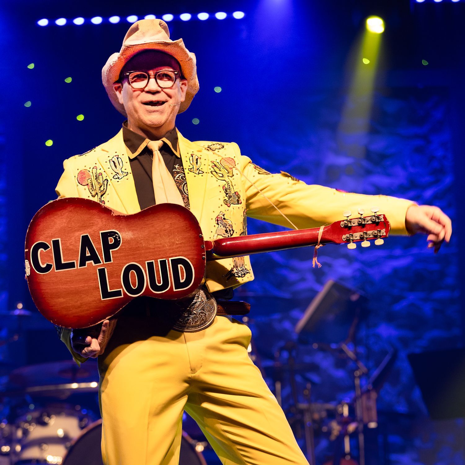 A man with long hair is playing a violin on a stage.