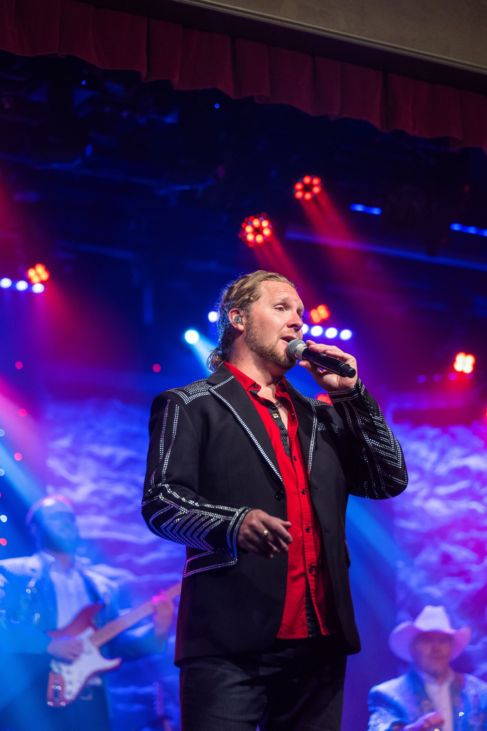 A man in a suit is singing into a microphone on a stage.