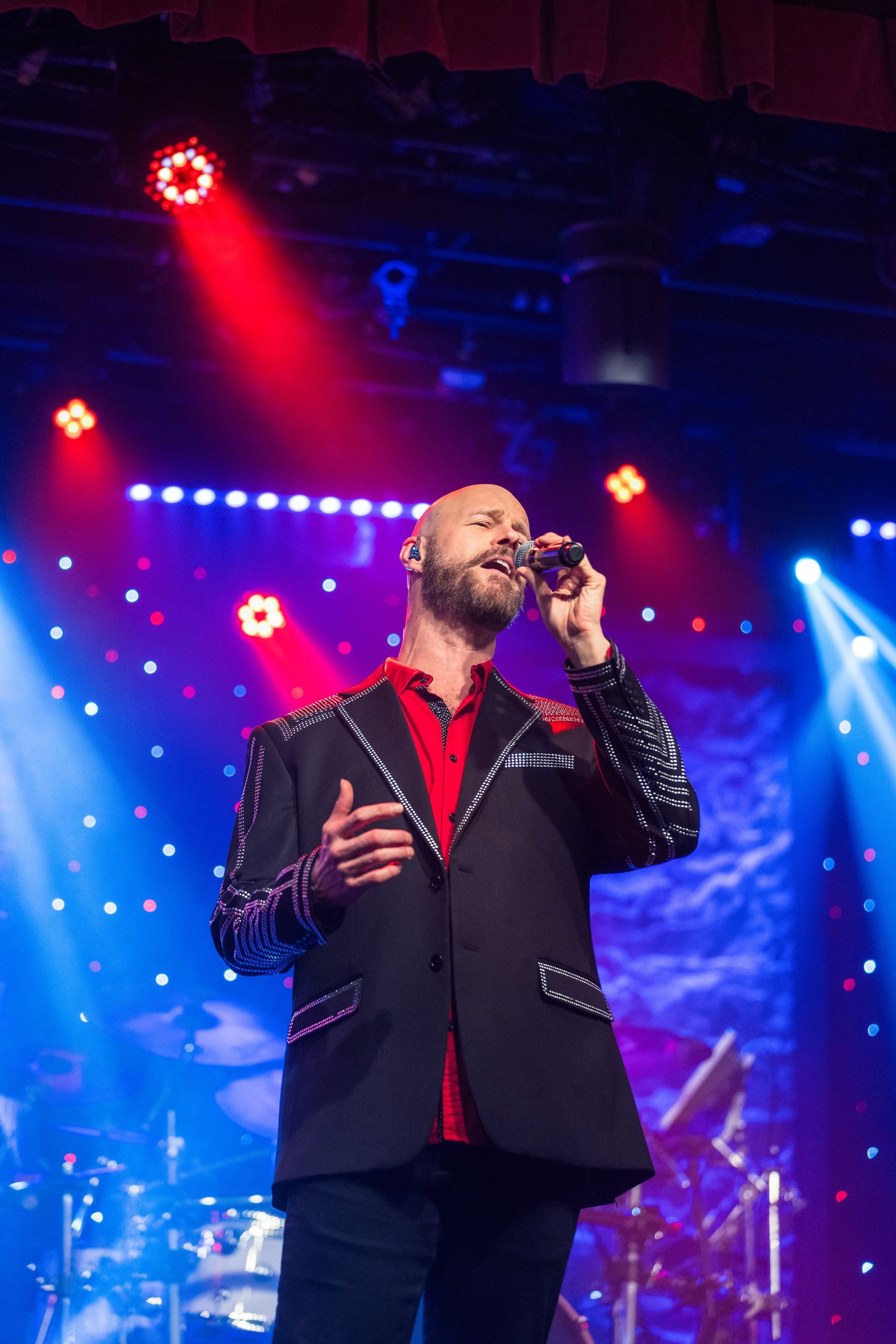 A man in a suit is singing into a microphone on a stage.