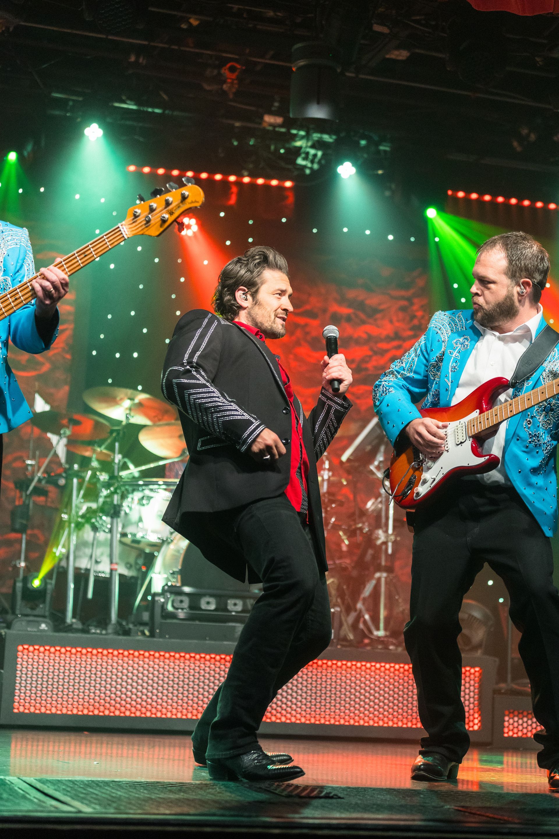 A group of men are playing guitars and singing on a stage.