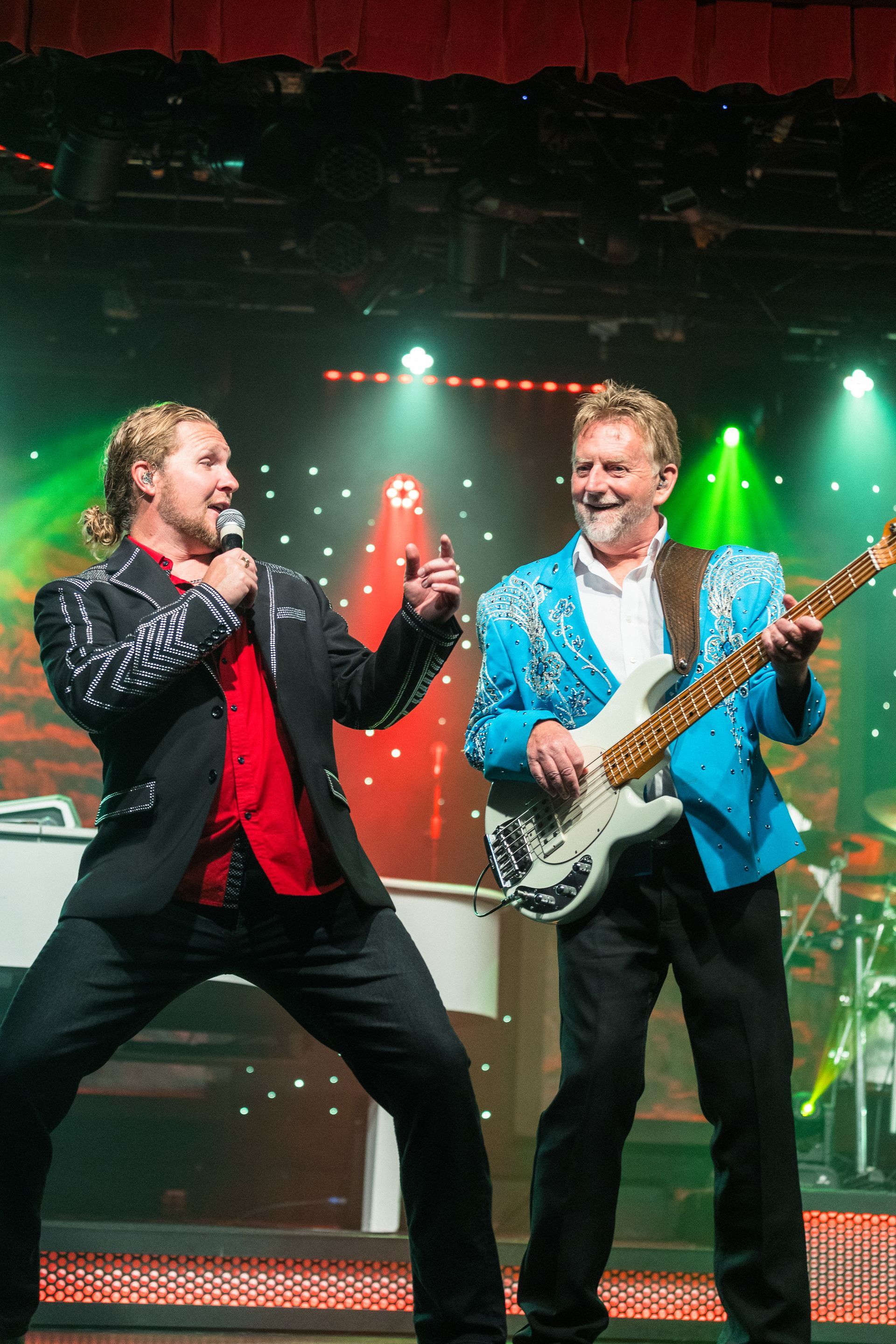 Two men are singing and playing guitar on a stage.