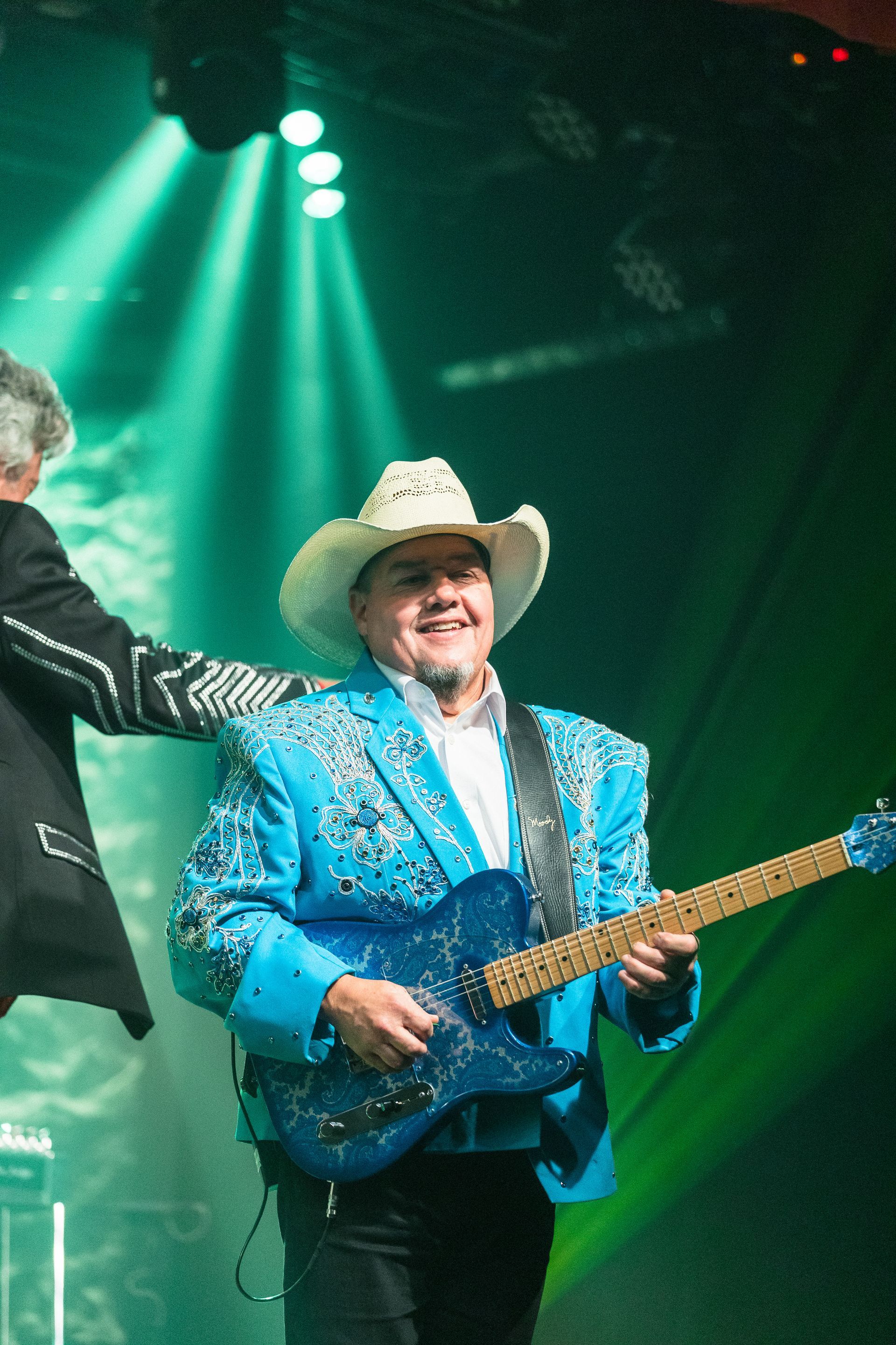 A man in a cowboy hat is playing a guitar on stage