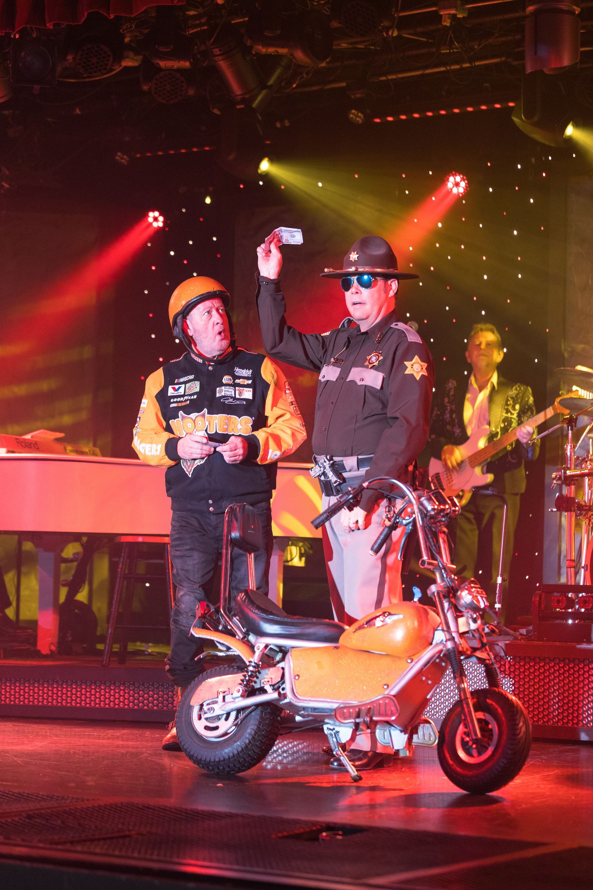 Two men standing next to a motorcycle on a stage