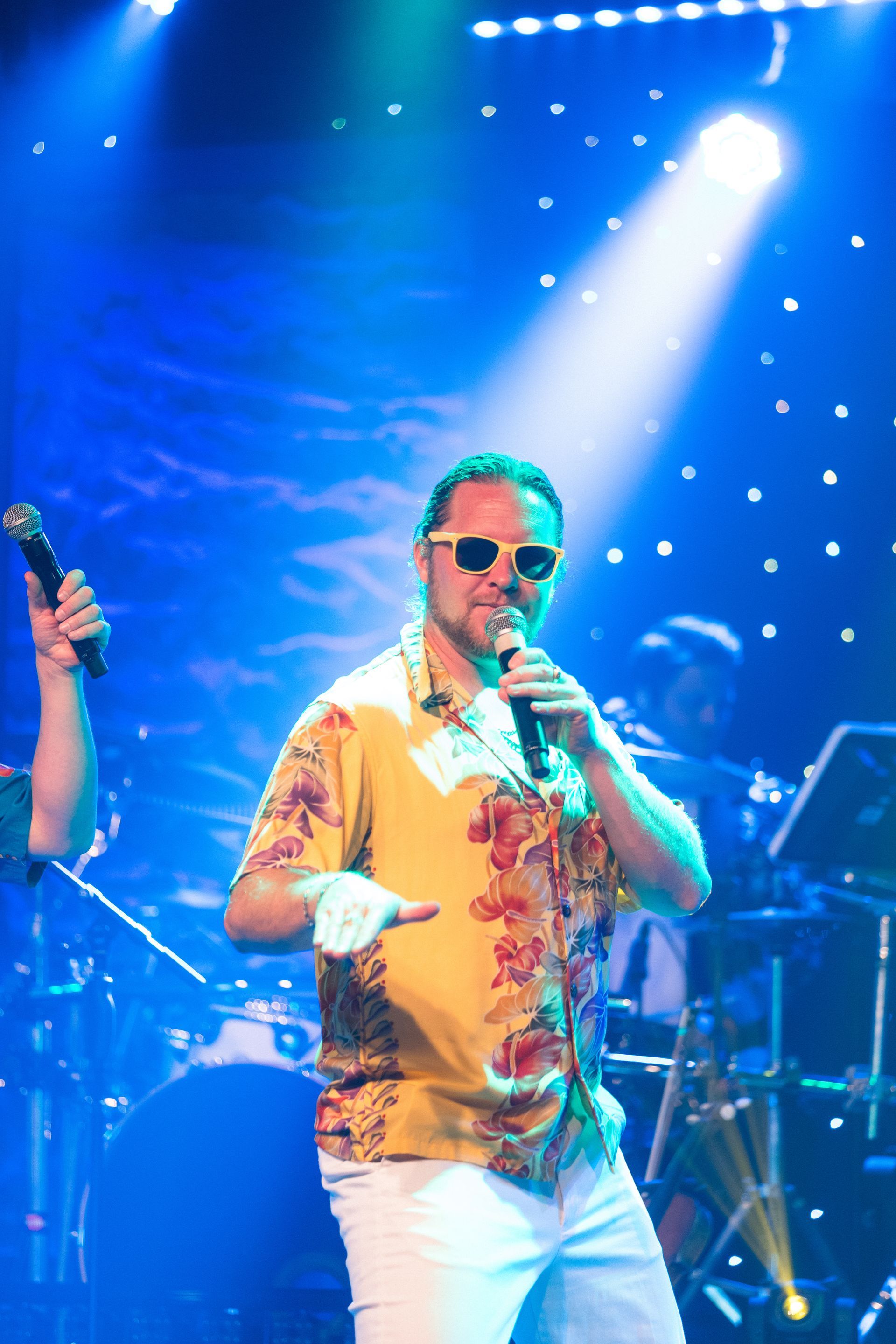 A man in a yellow shirt is singing into a microphone on a stage.