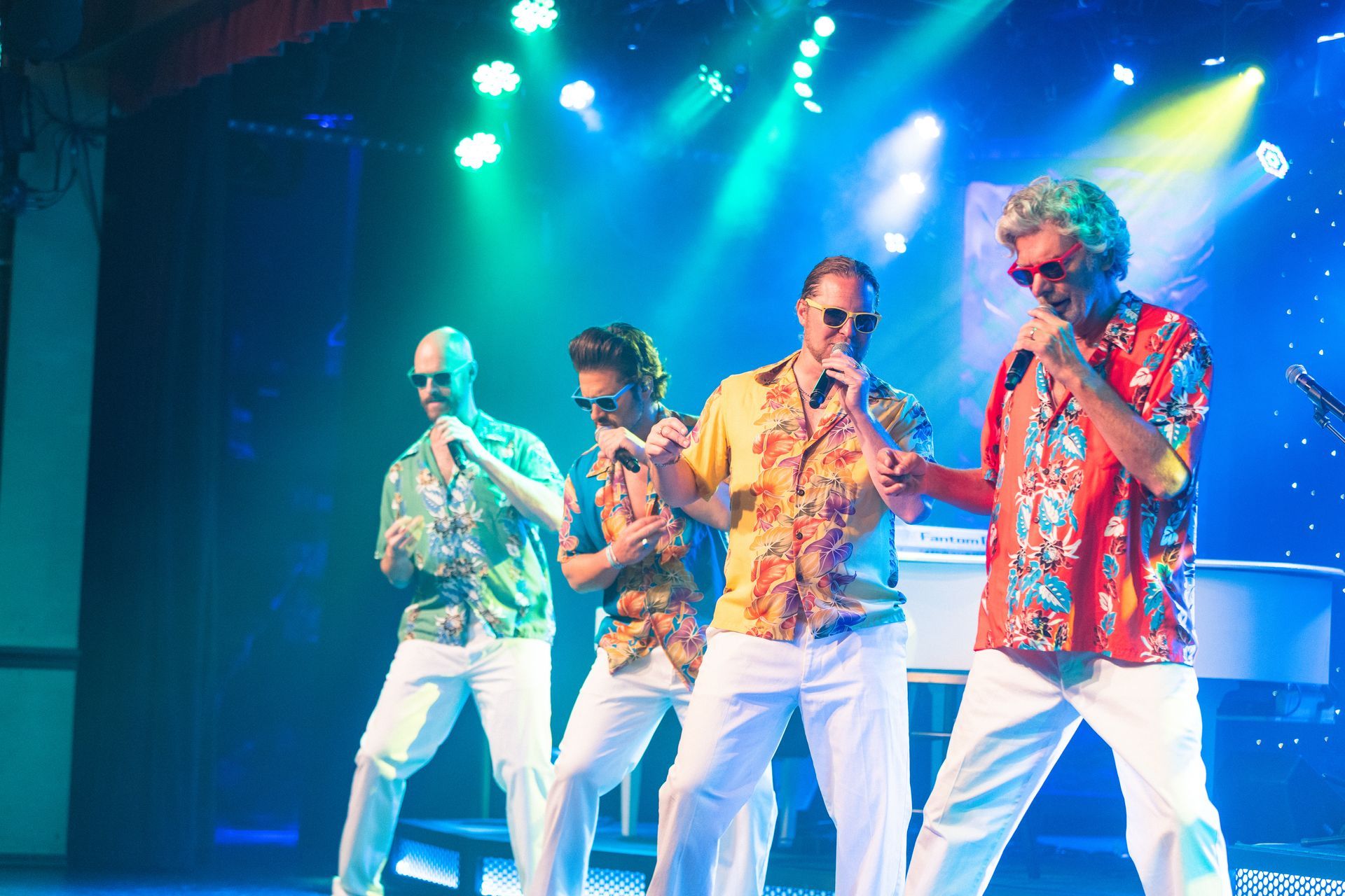 A group of men are singing into microphones on a stage.