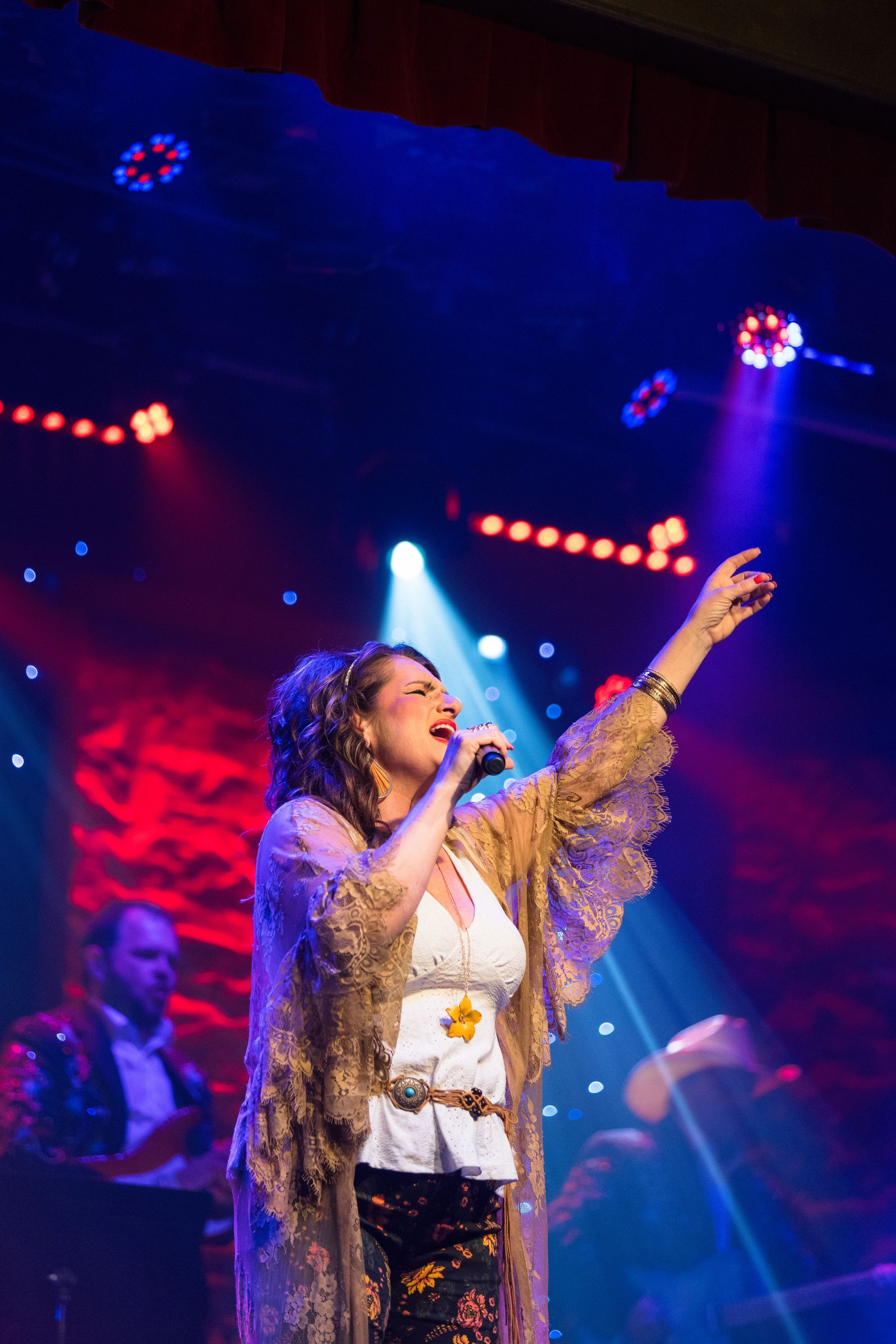 A woman is singing into a microphone on a stage.