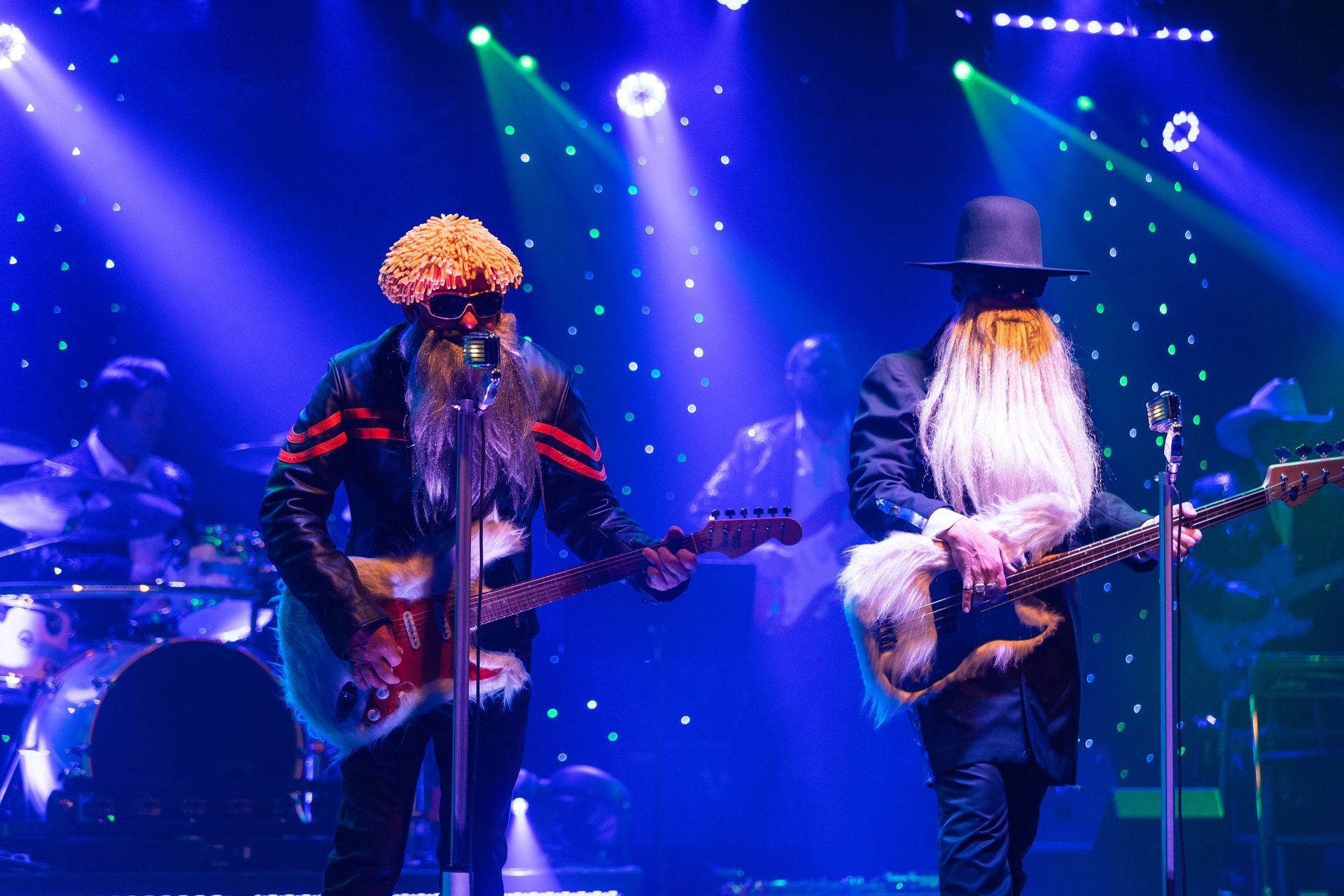 Two men are playing guitars and singing into microphones on a stage.