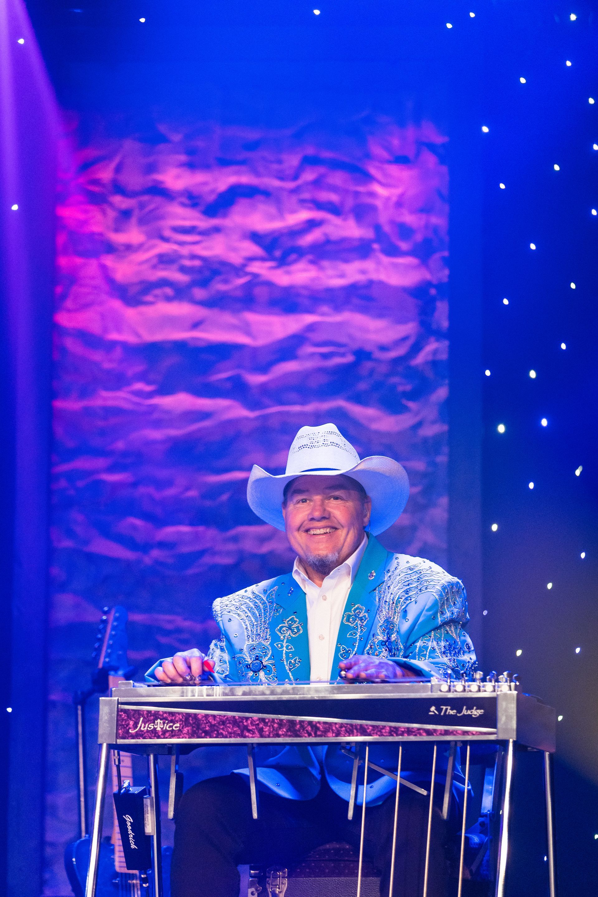 A man in a cowboy hat is playing a keyboard on stage