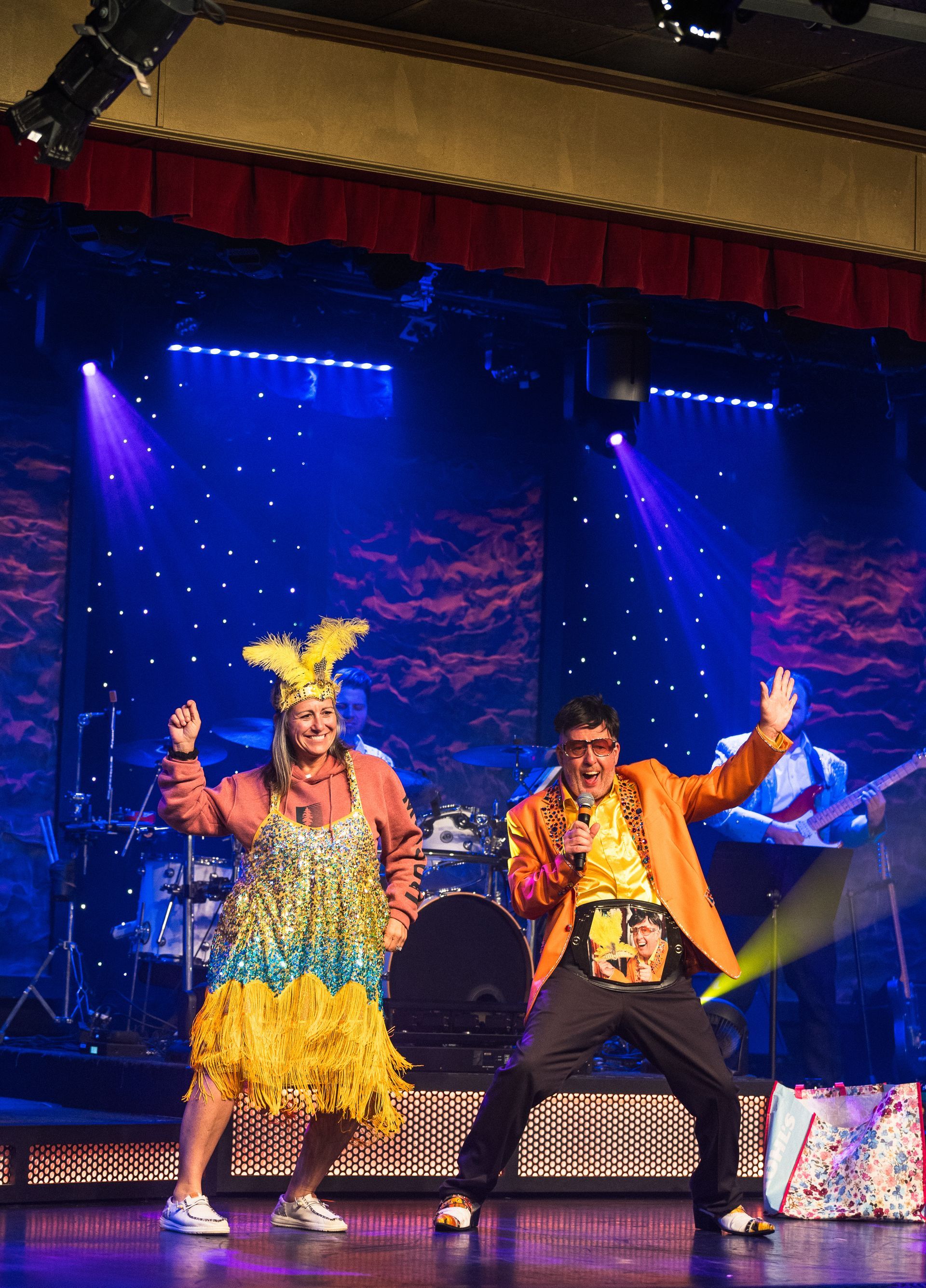 A man and a woman are dancing on a stage in front of a drum set.