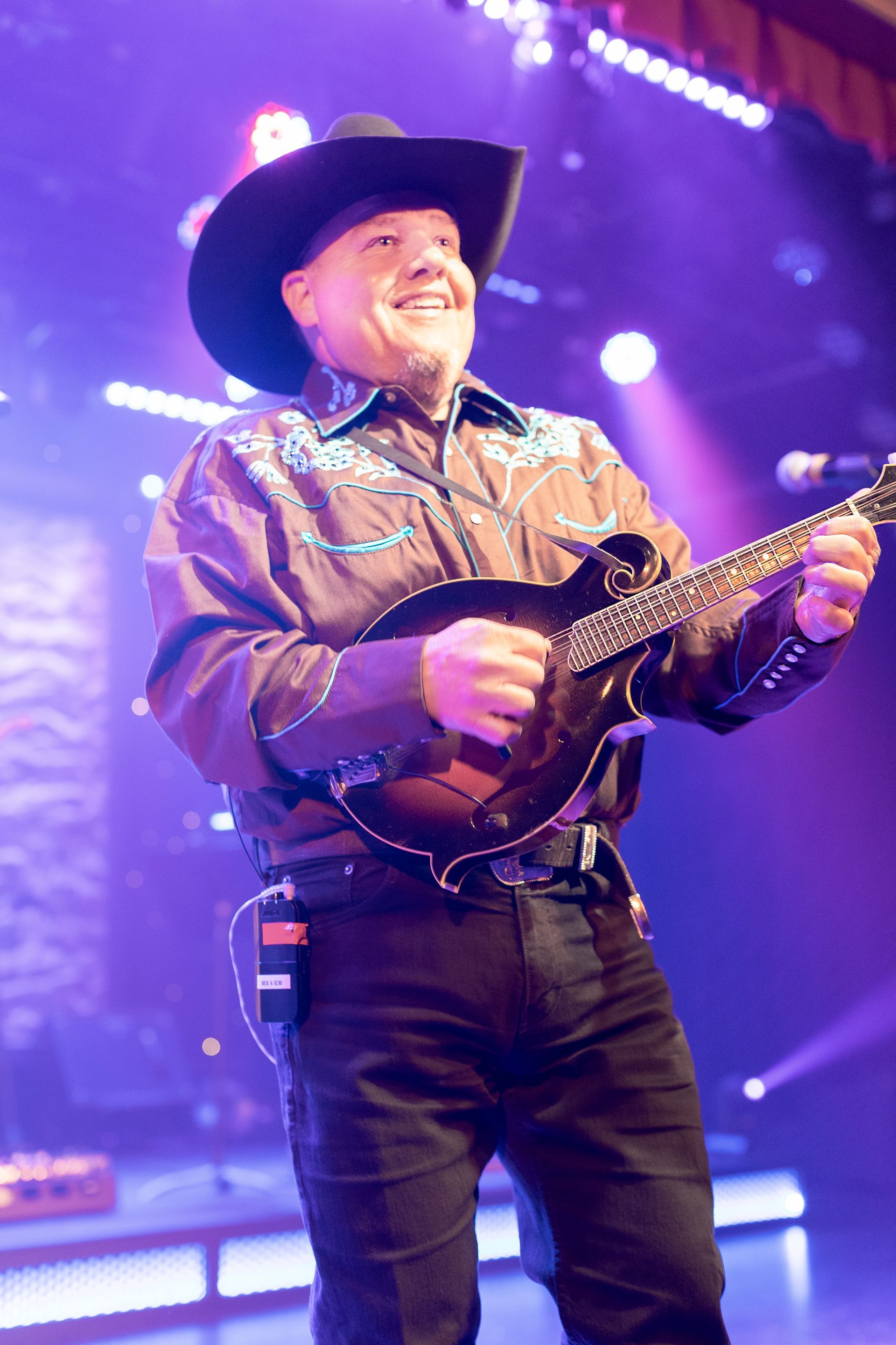 A man in a cowboy hat is playing a guitar on a stage.