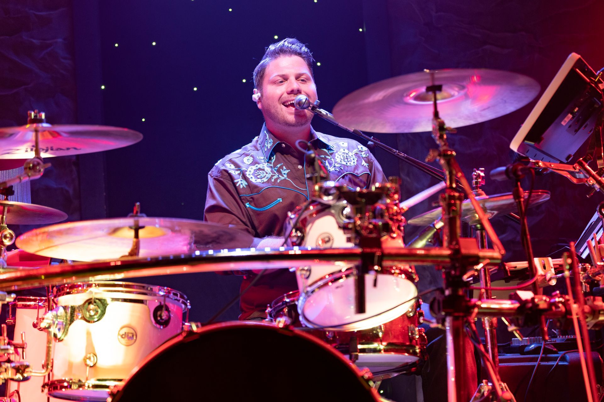 A man is playing drums and singing into a microphone