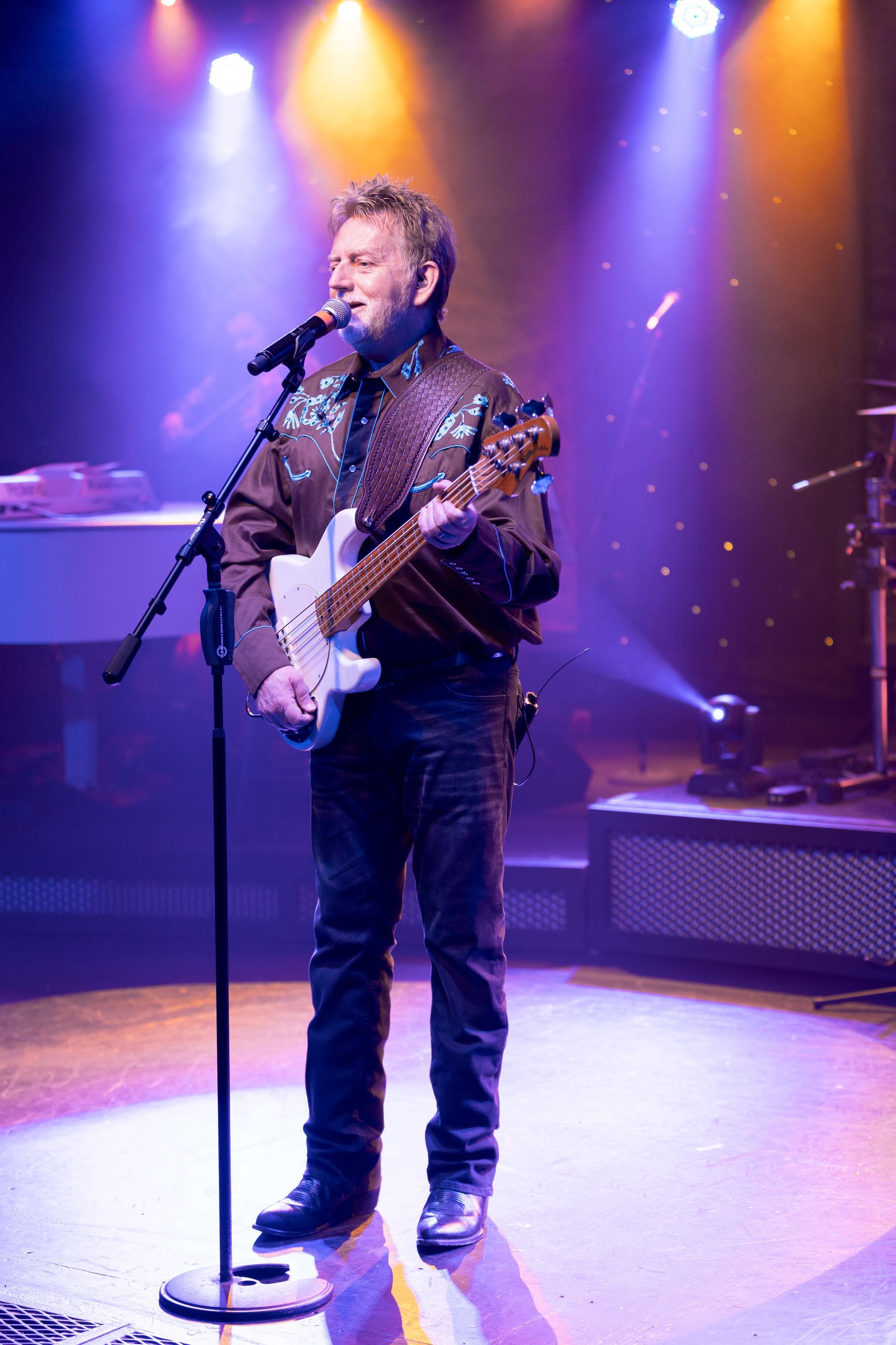 A man is playing a guitar and singing into a microphone on a stage.