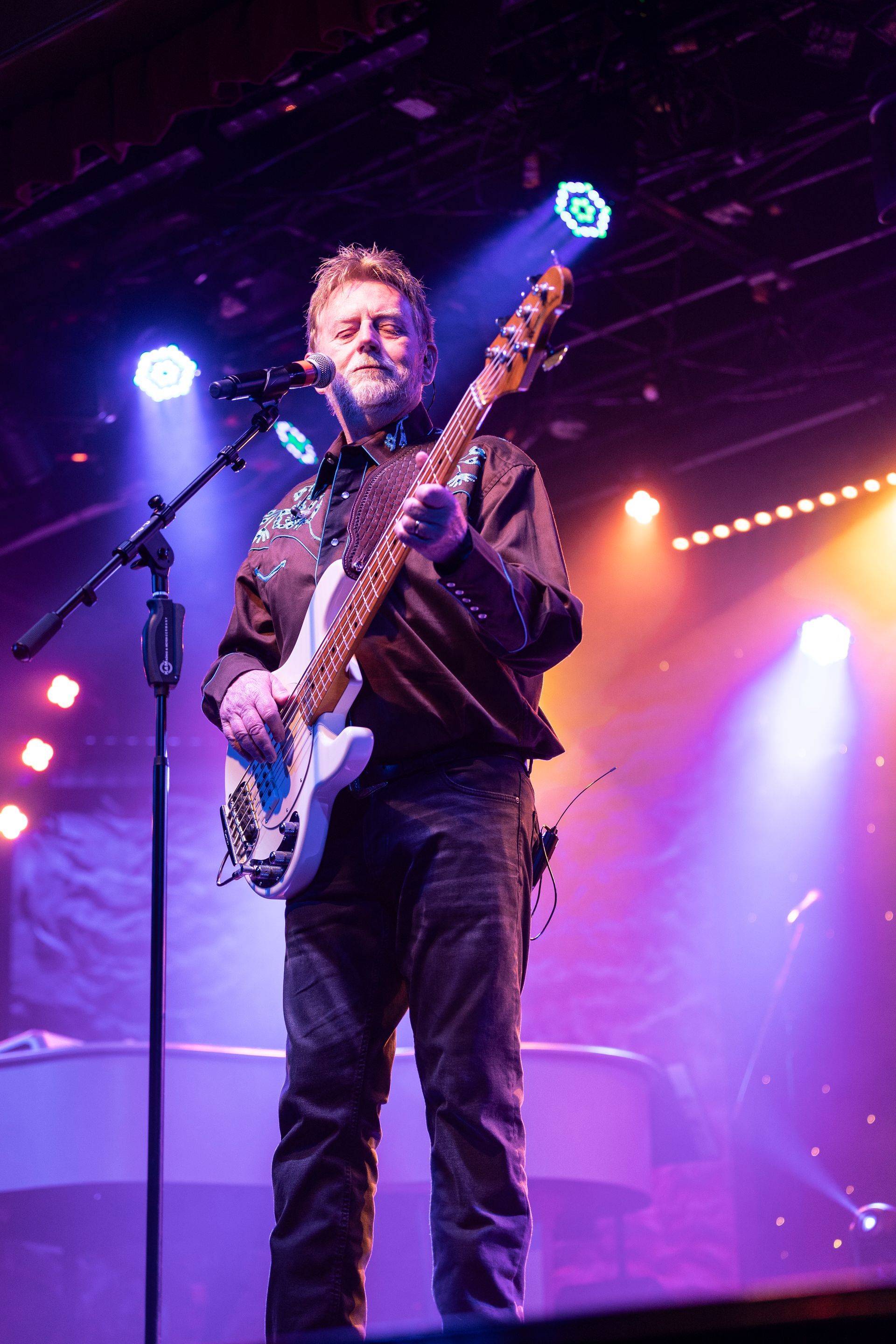 A man is playing a guitar and singing into a microphone on a stage.