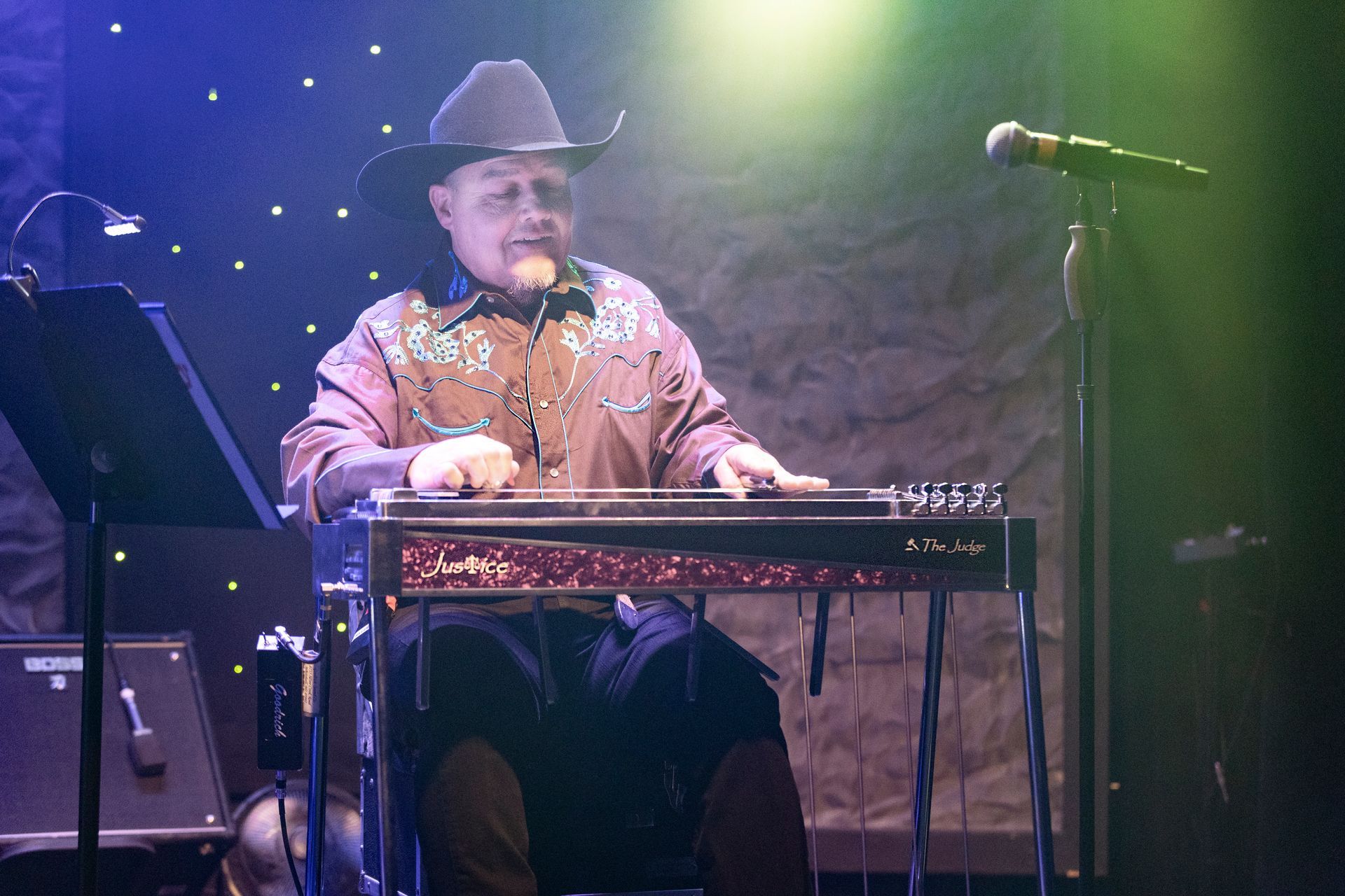 A man in a cowboy hat is playing a guitar on a stage.