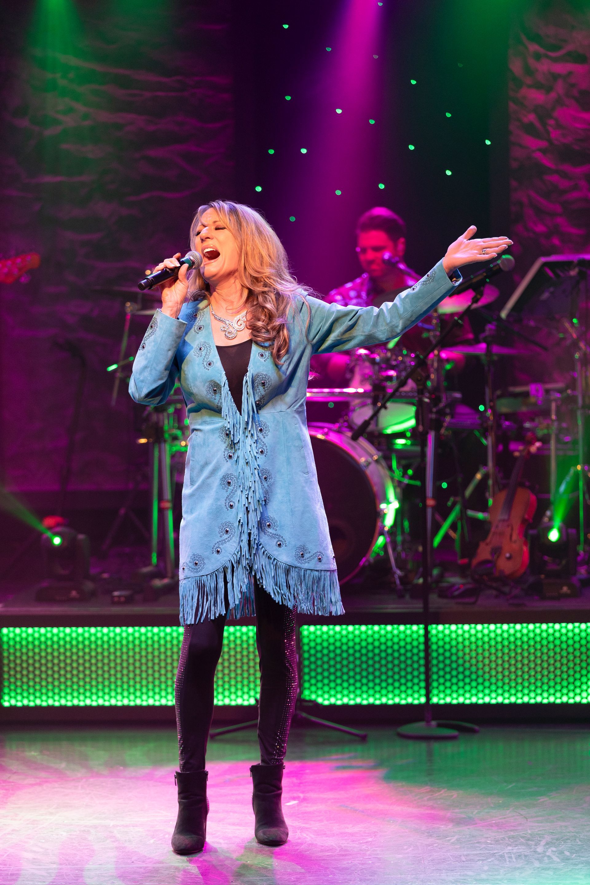 A woman is singing into a microphone on a stage.