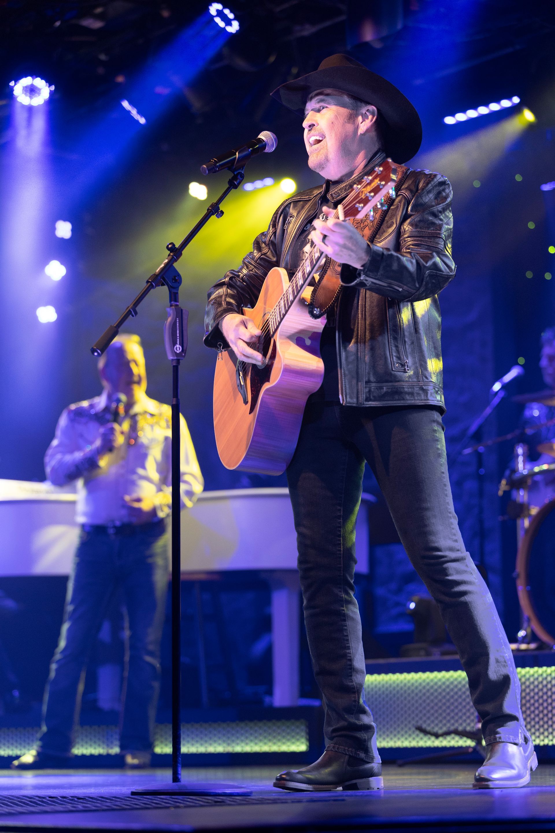 A man is playing a guitar and singing into a microphone on a stage.