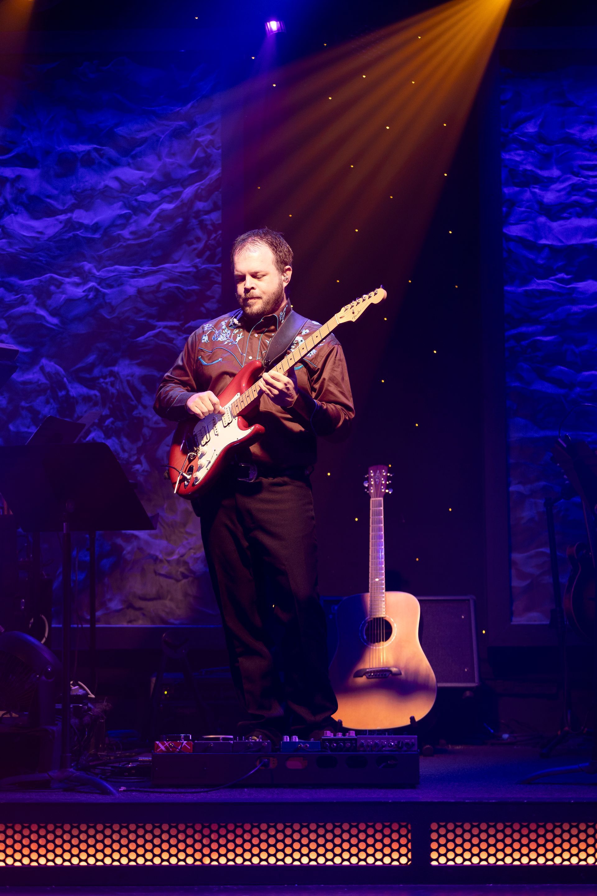 A man is playing an electric guitar on a stage.