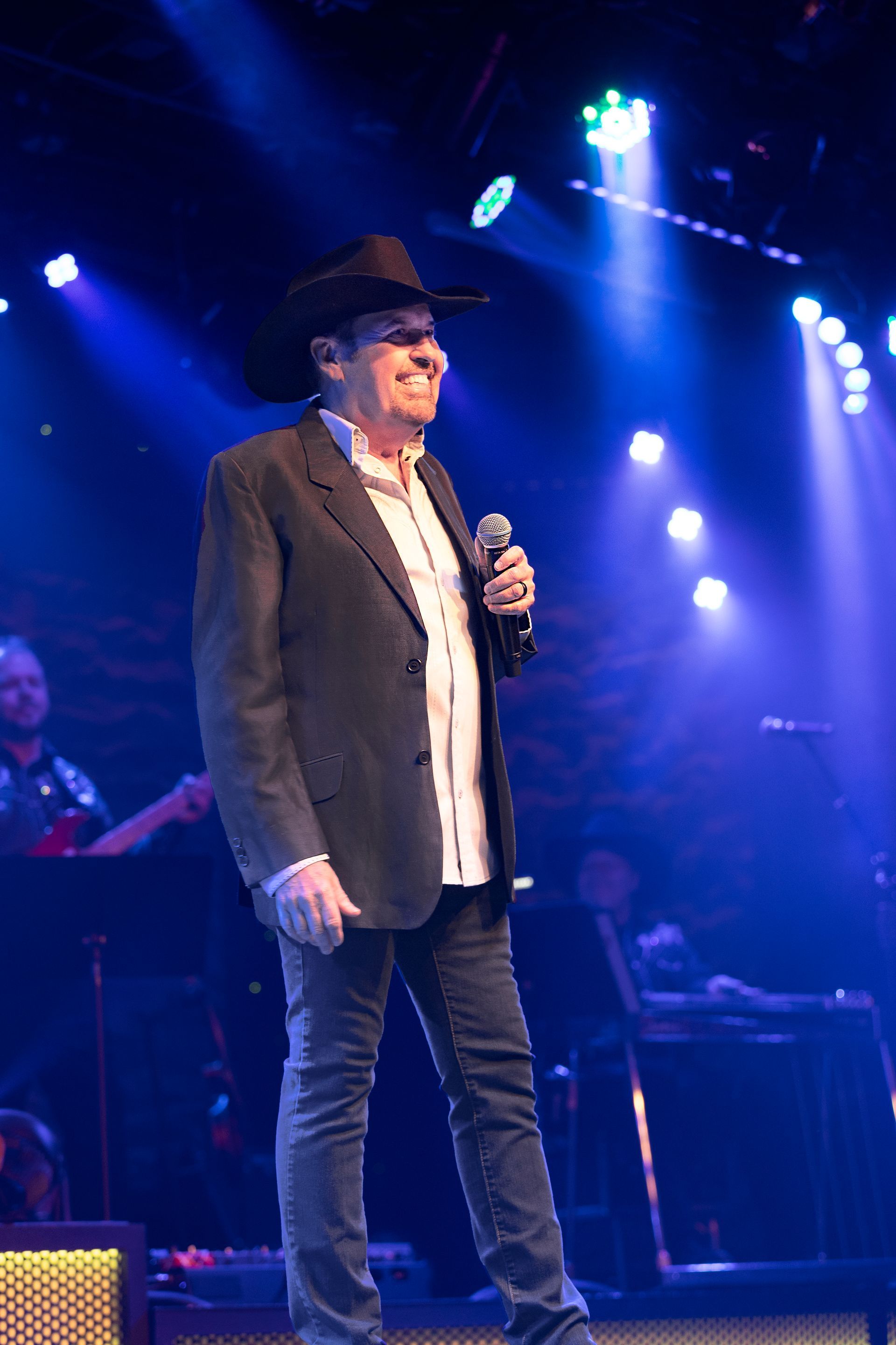 A man in a cowboy hat is singing into a microphone on a stage.