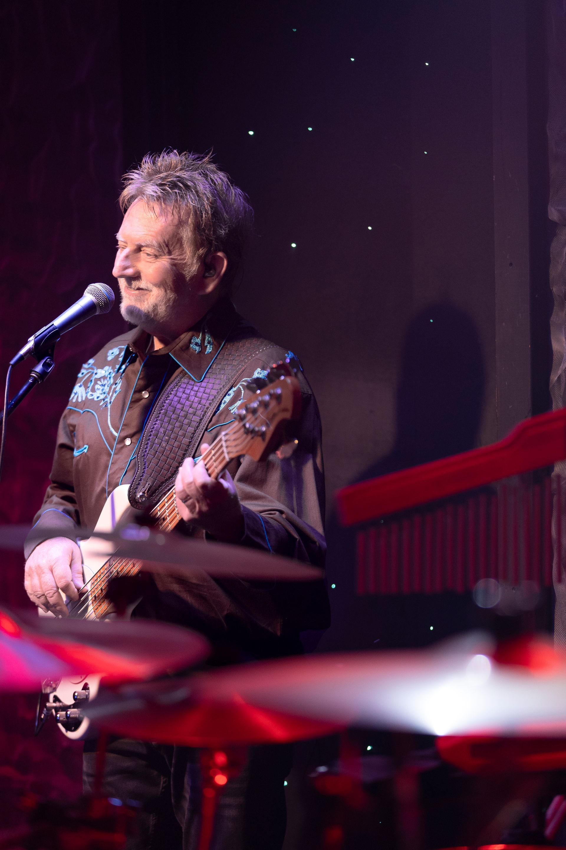 A man is playing a guitar and singing into a microphone on a stage.