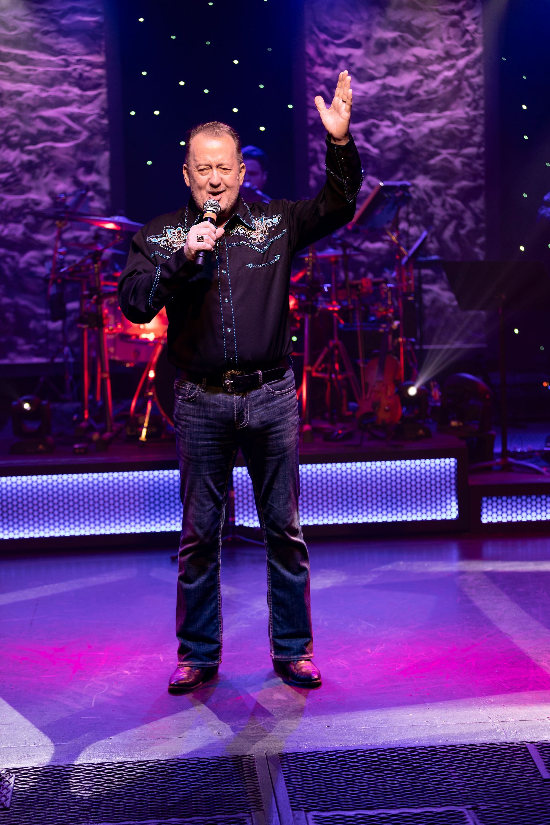 A man is standing on a stage holding a microphone.