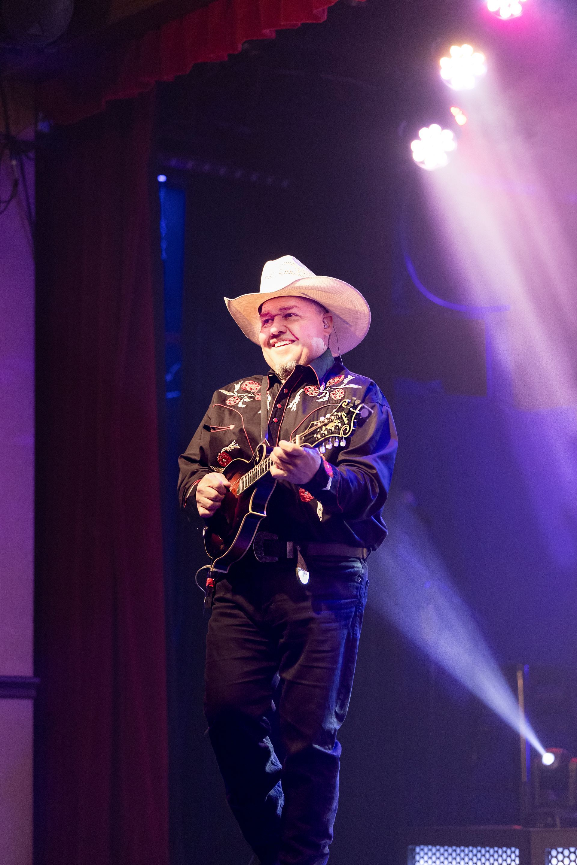 A man in a cowboy hat is playing a guitar on a stage.