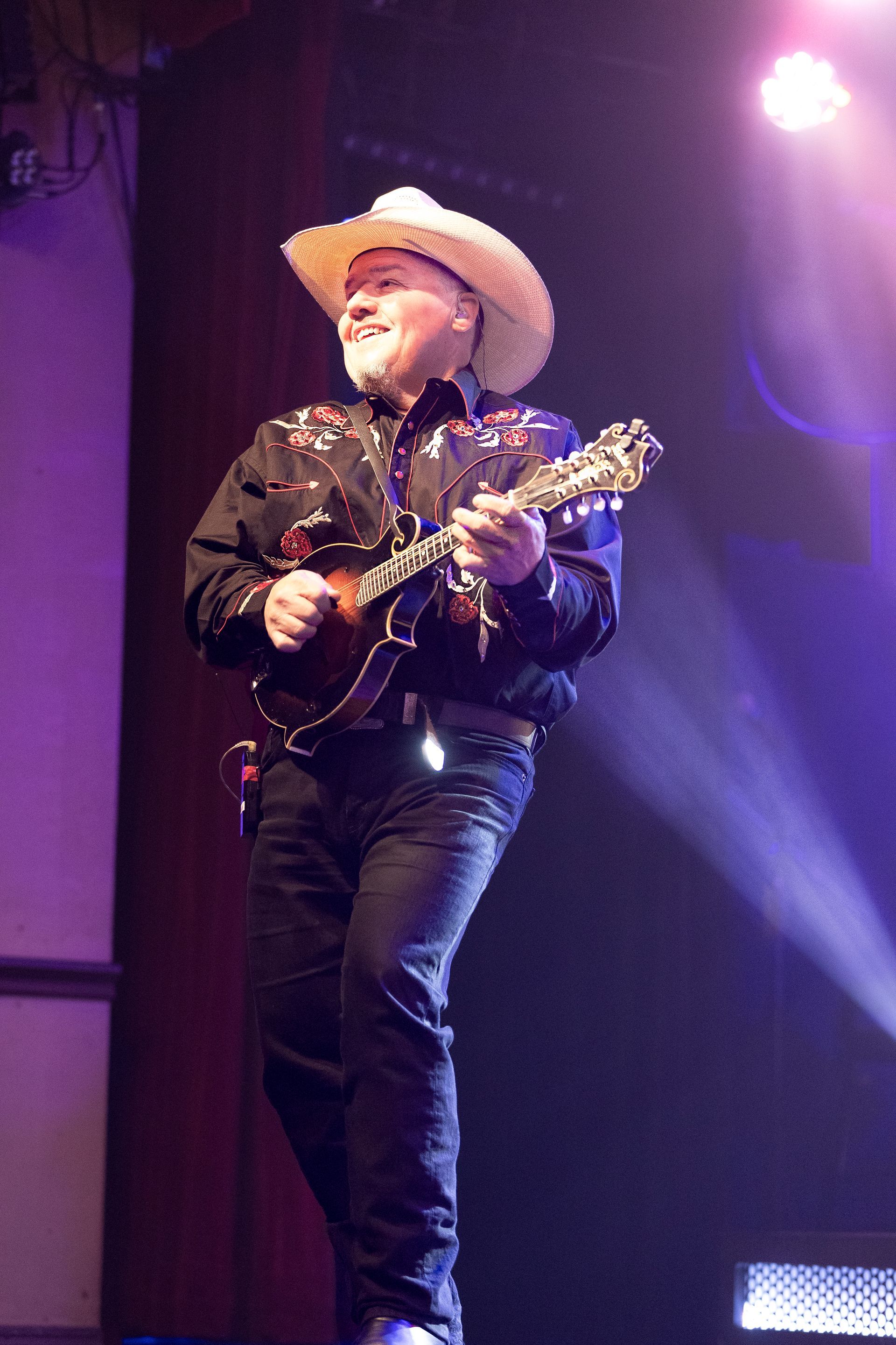 A man in a cowboy hat is playing a guitar on a stage.