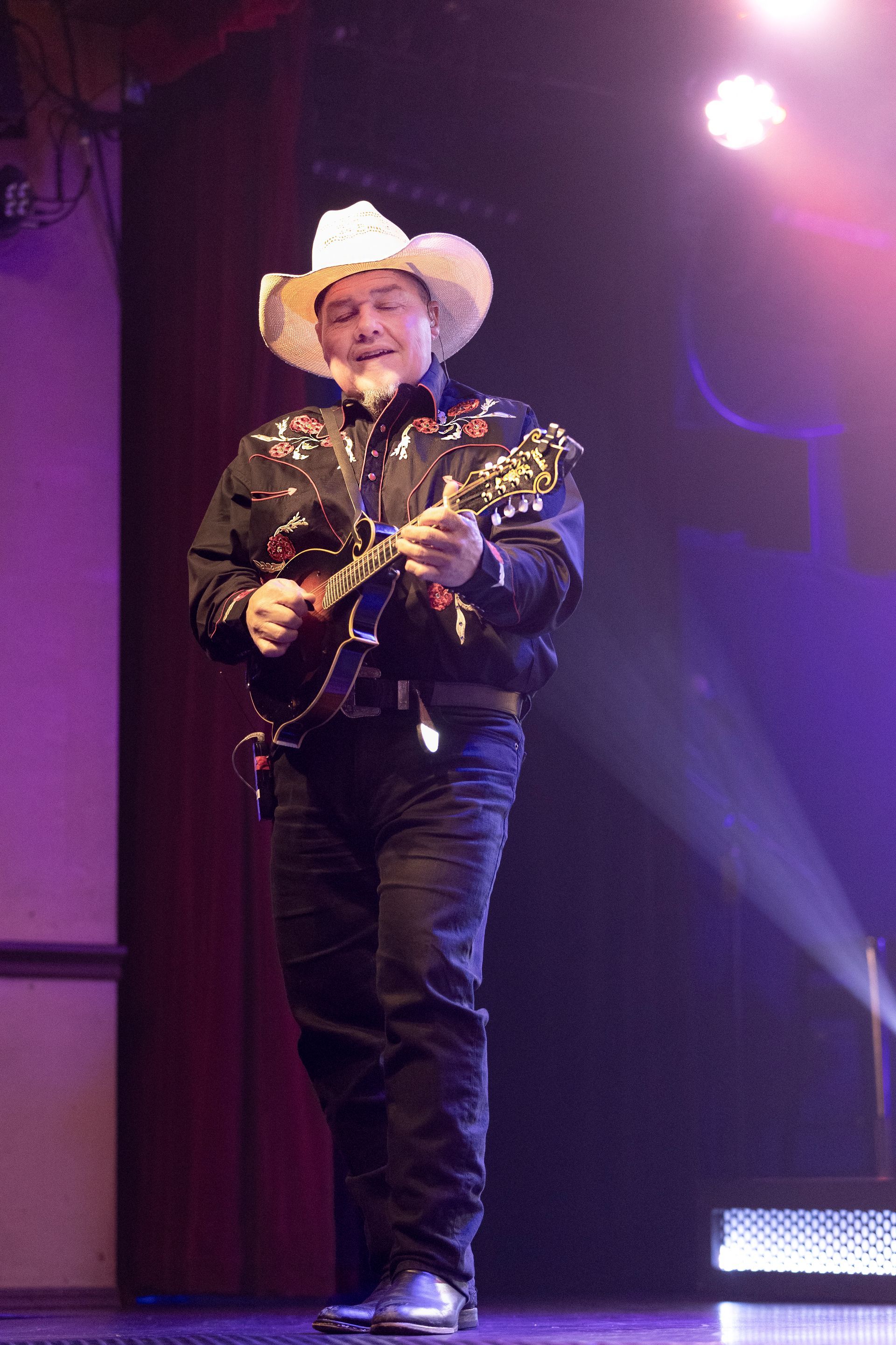 A man in a cowboy hat is playing a guitar on a stage.