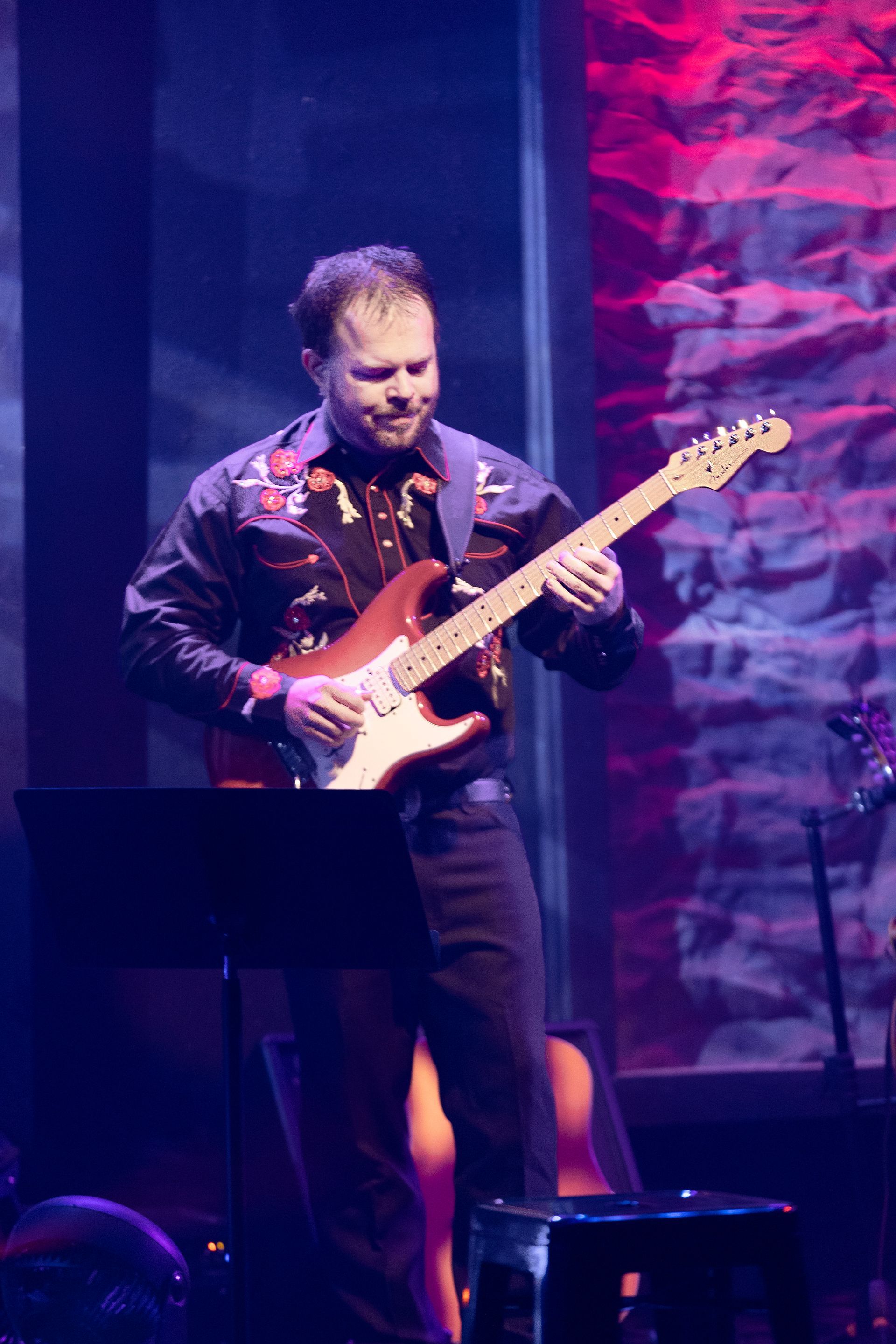 A man is playing an electric guitar on a stage.