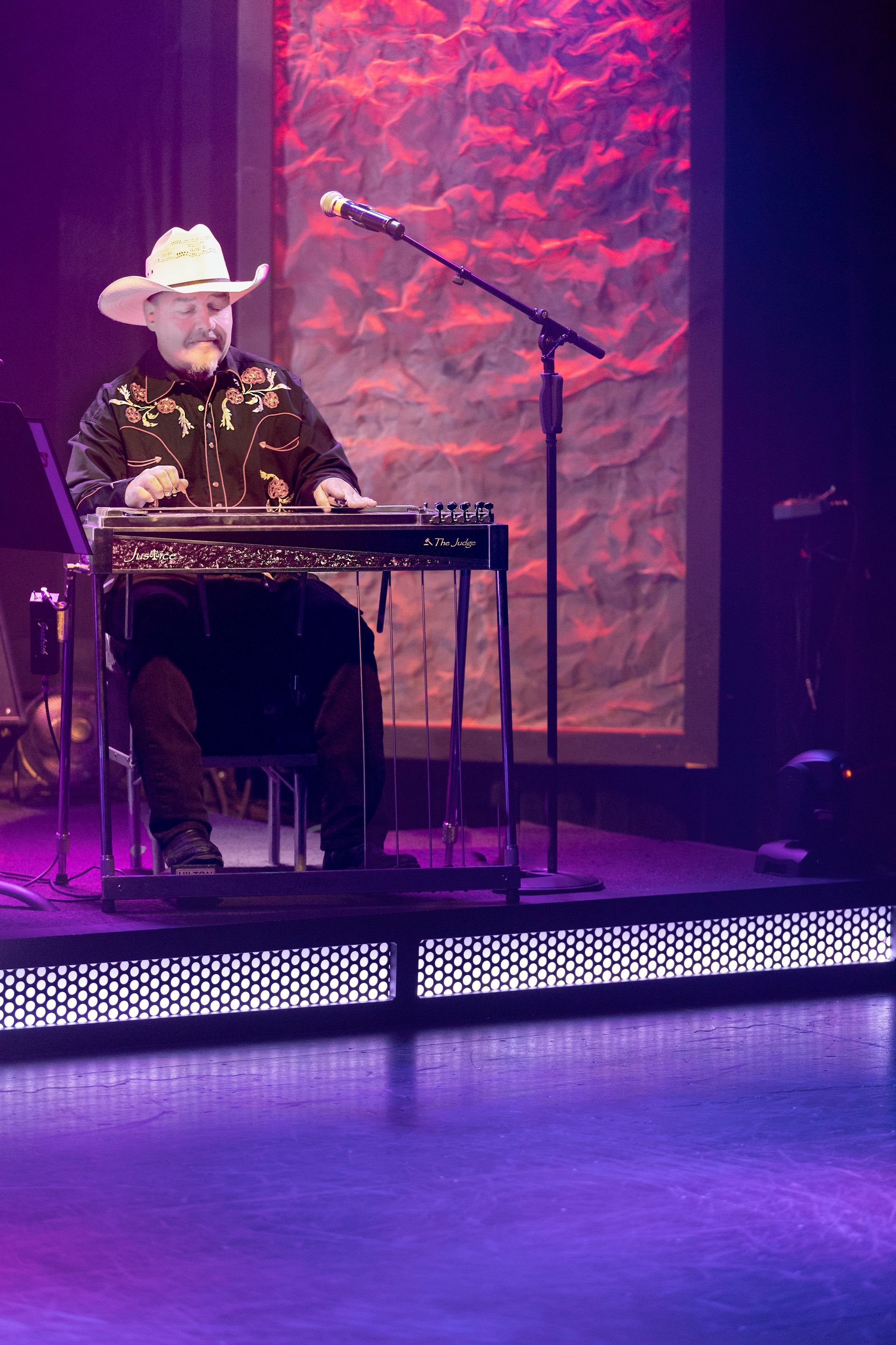 A man in a cowboy hat is playing a keyboard on a stage.