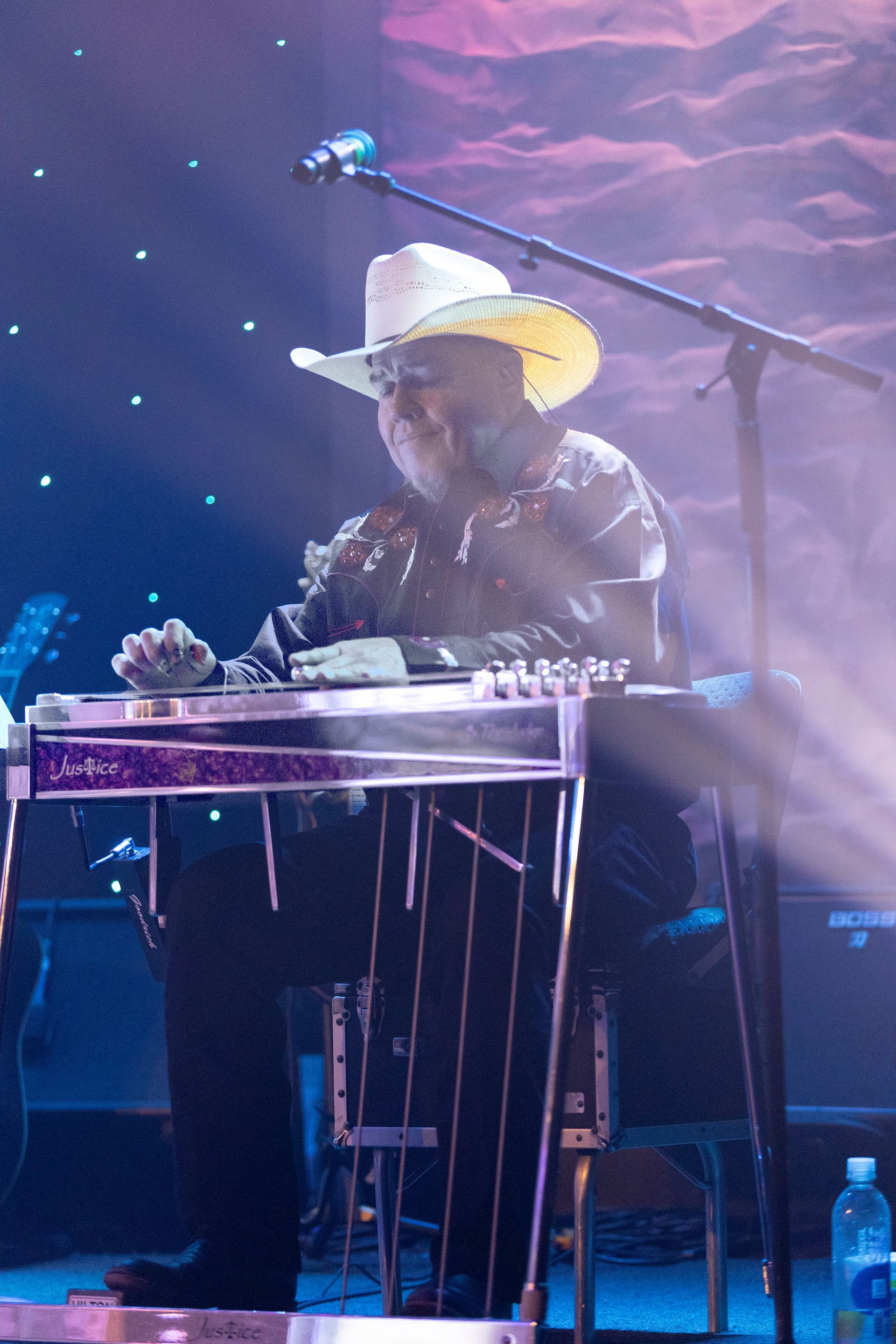 A man in a cowboy hat is playing a guitar on stage