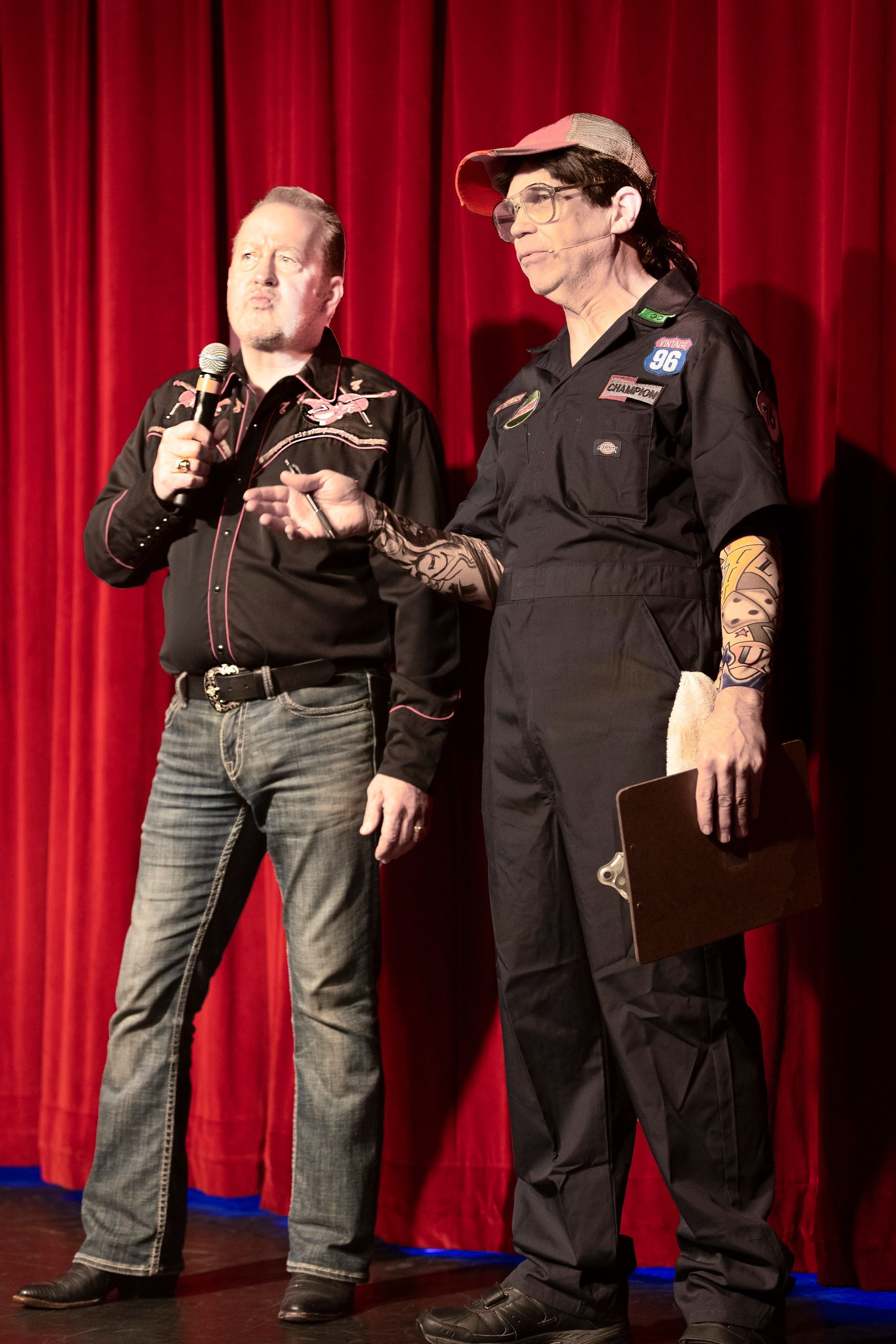 A man is holding a microphone while standing next to a woman on a stage.