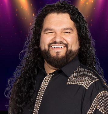 A man with long hair and a beard is wearing a black shirt and smiling.