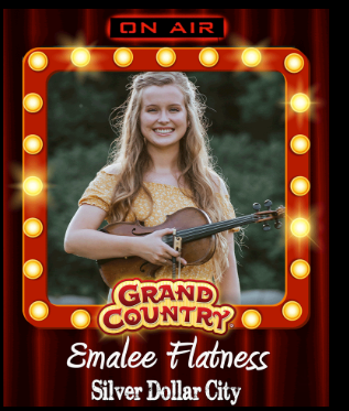A woman is holding a guitar in front of a red curtain.
