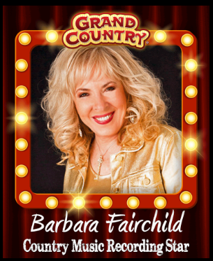 A woman is holding a guitar in front of a red curtain.