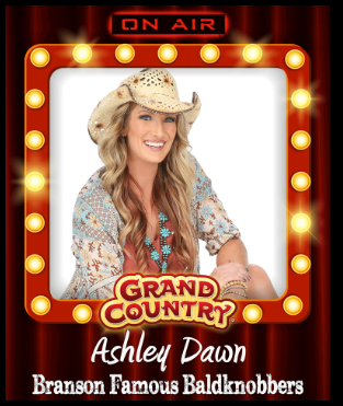 A woman is holding a guitar in front of a red curtain.