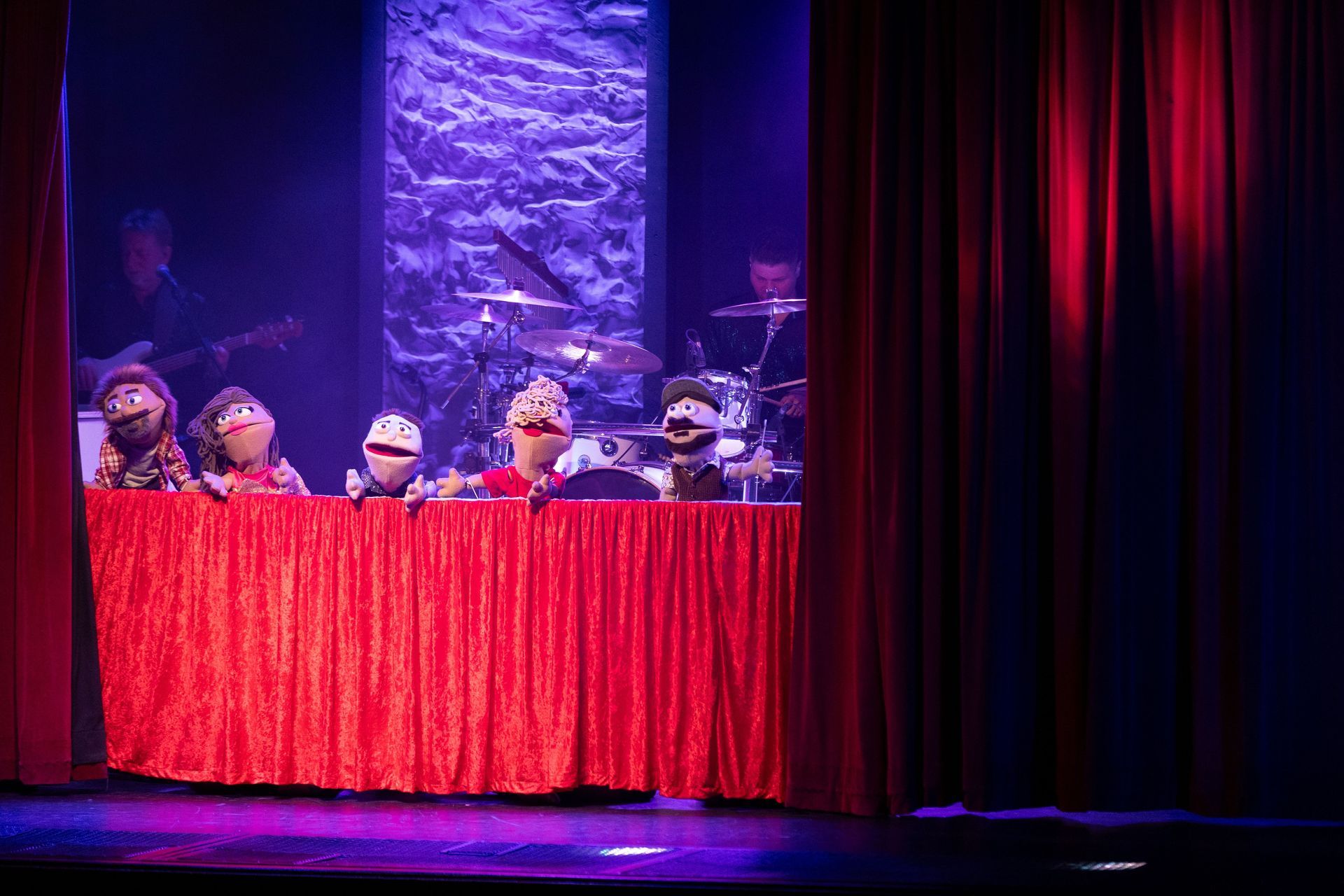 A group of muppets are sitting at a table on a stage.