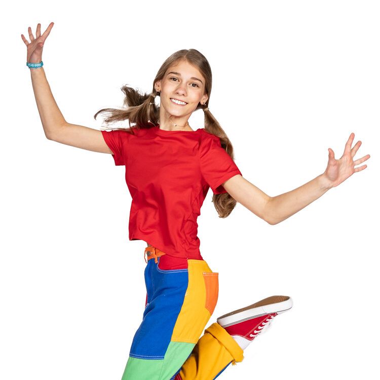 A girl in a red shirt and rainbow pants is jumping in the air.