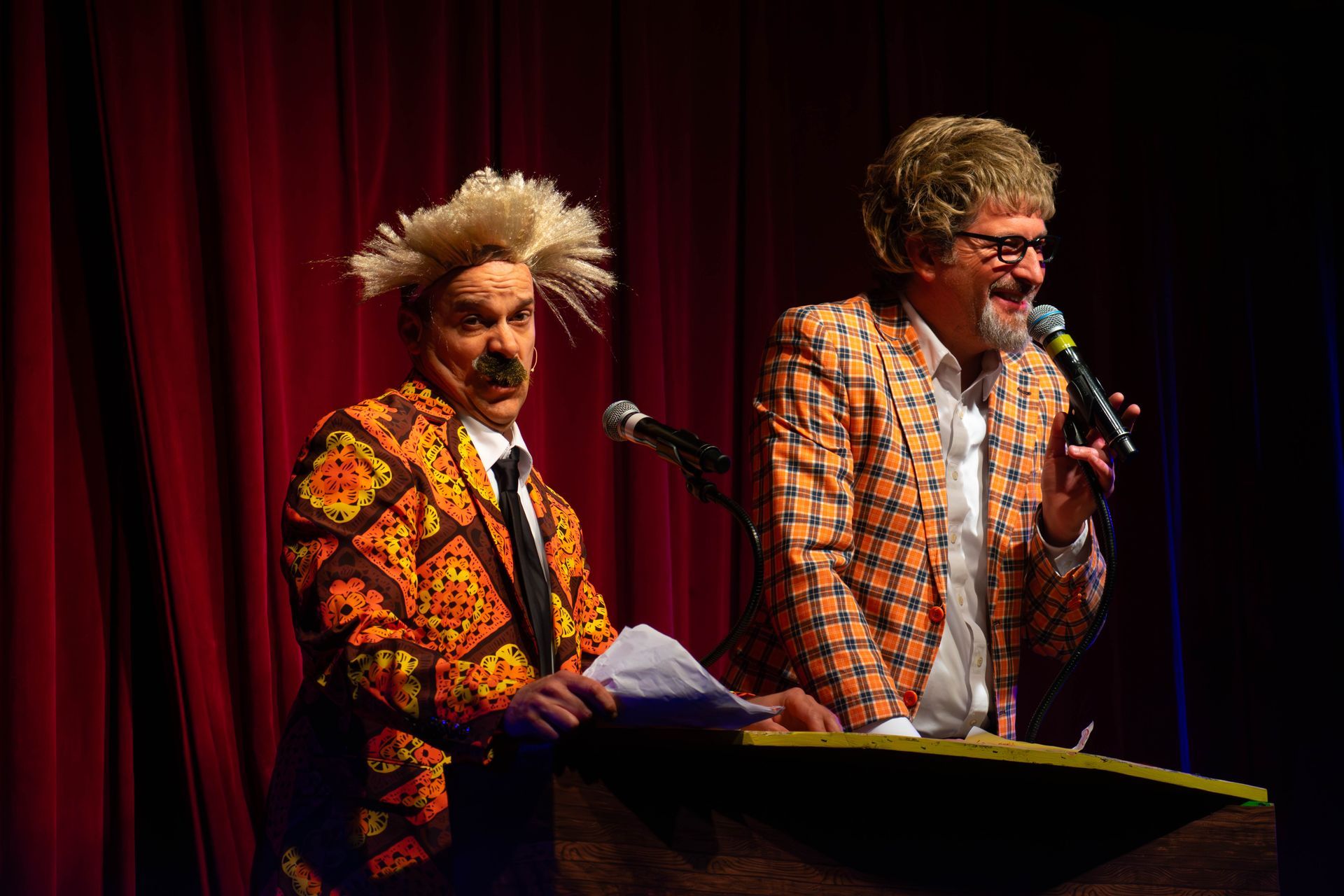 Two men are standing next to each other on a stage holding microphones.