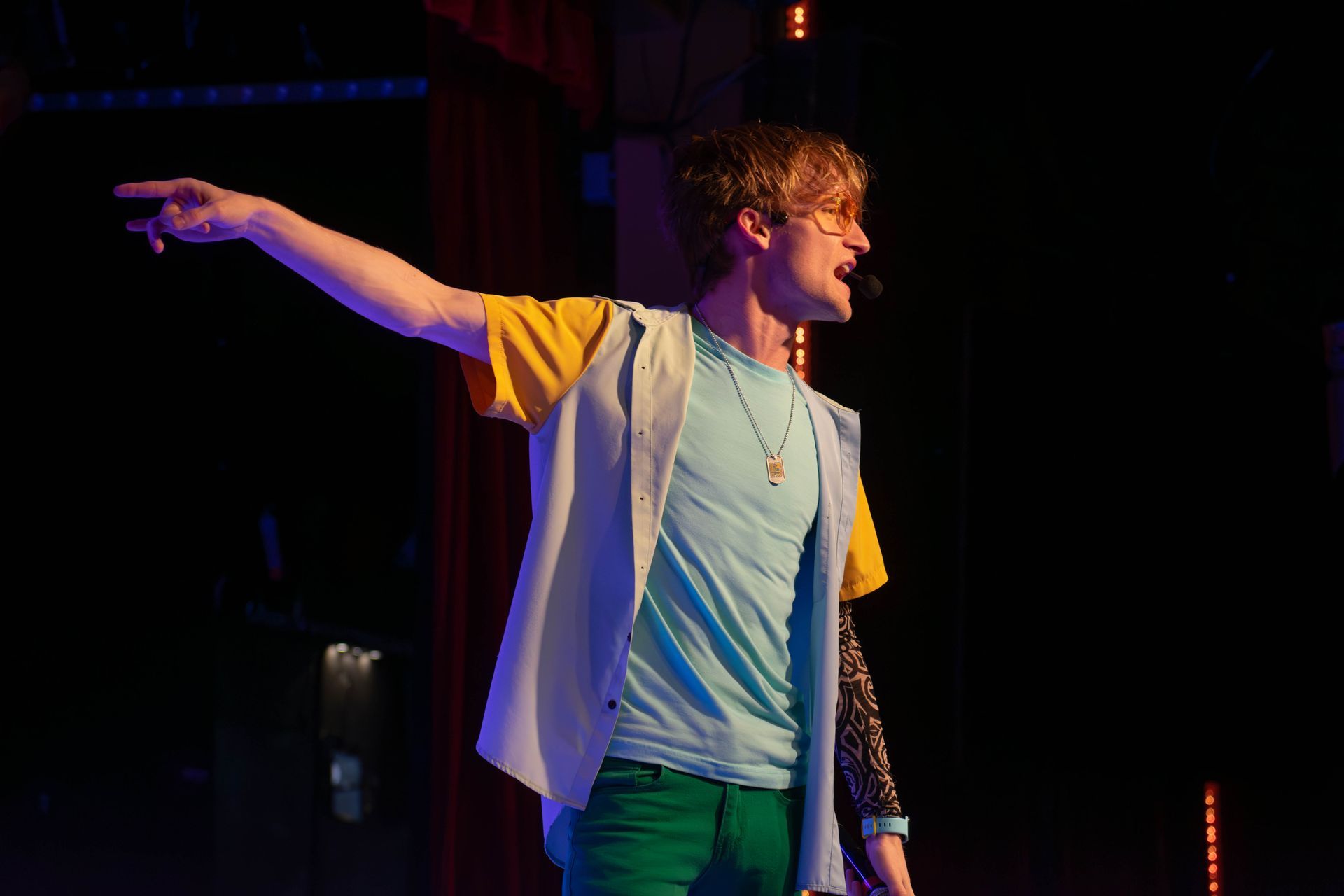 A man is standing on a stage with his arms outstretched.