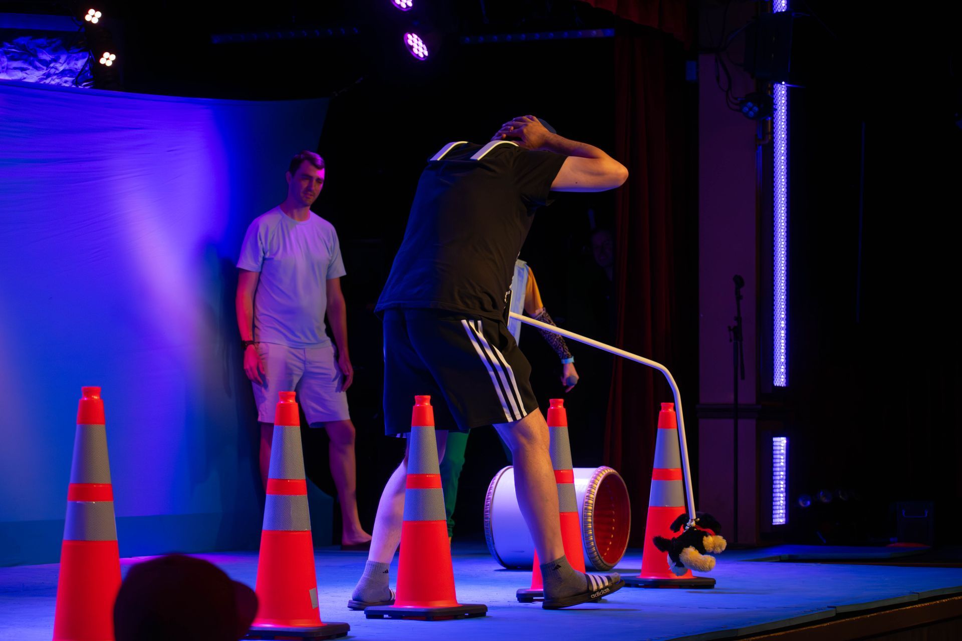 A man is standing on a stage surrounded by traffic cones.