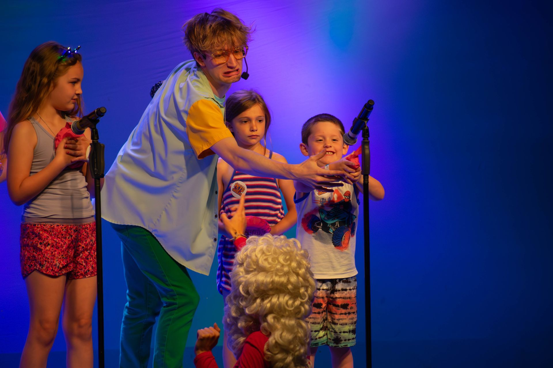 A group of children are standing in front of a microphone on a stage.